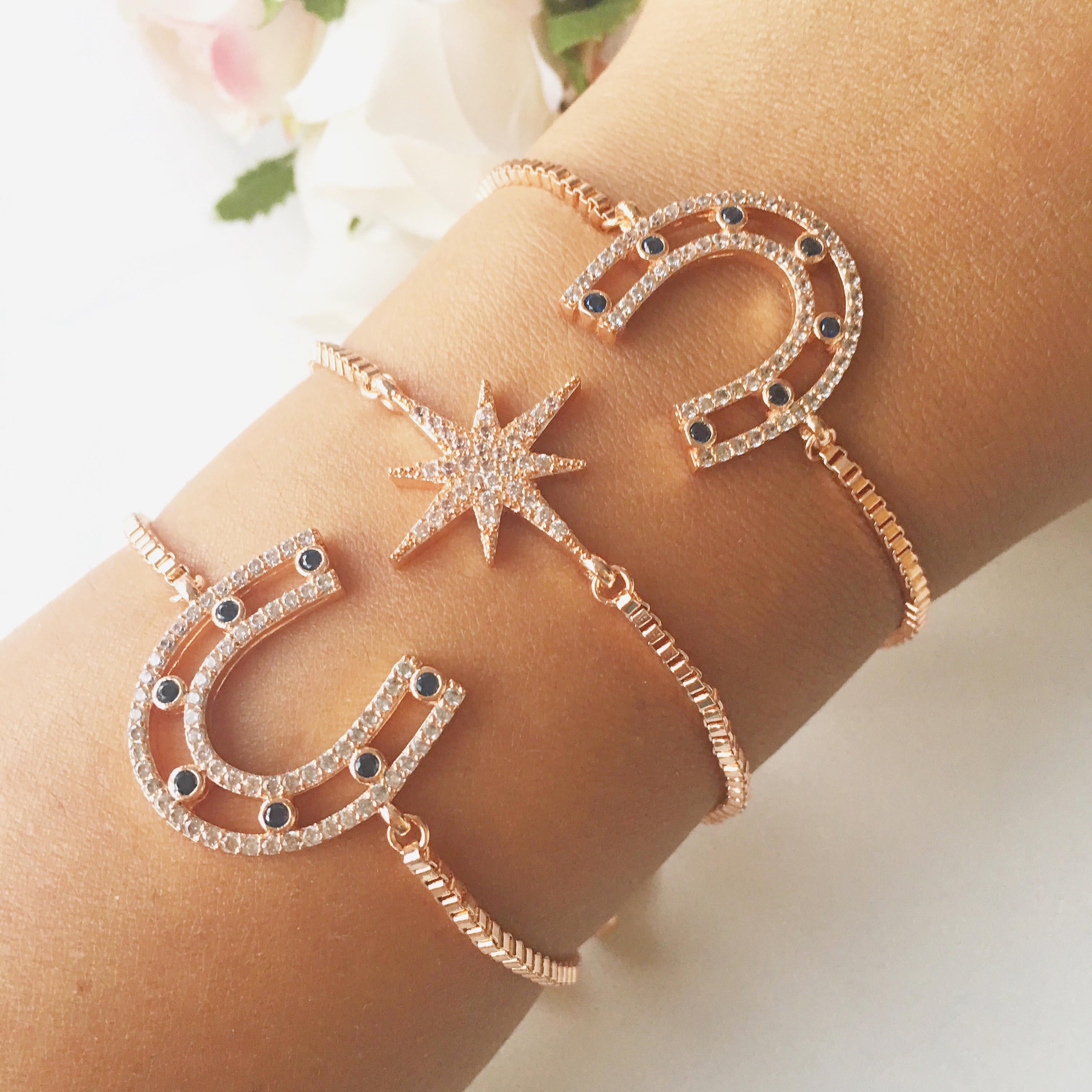 A beautiful rose gold bracelet featuring a horseshoe and star charm, adorned with sparkling zirconia stones, adjustable for all wrist sizes.