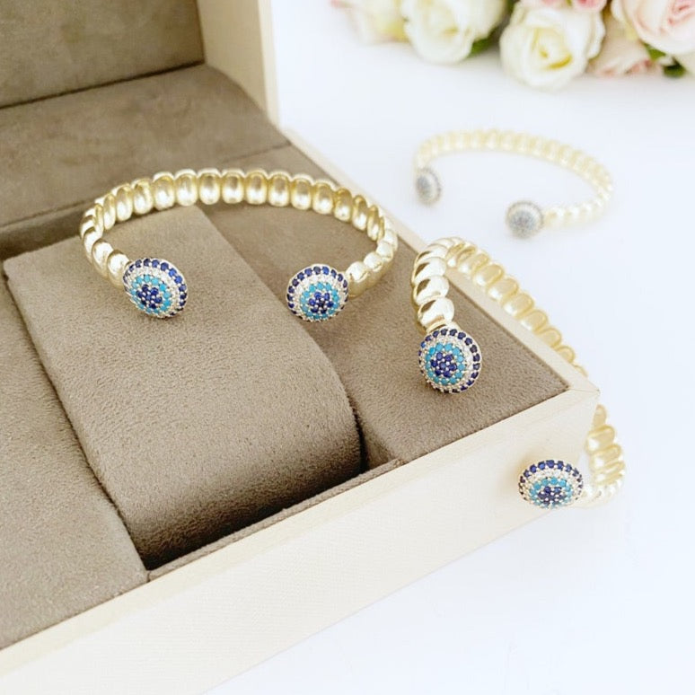 Luxury Evil Eye Bracelet featuring a gold twisted cuff and a movable zircon evil eye charm, showcasing its elegant design and adjustable fit.