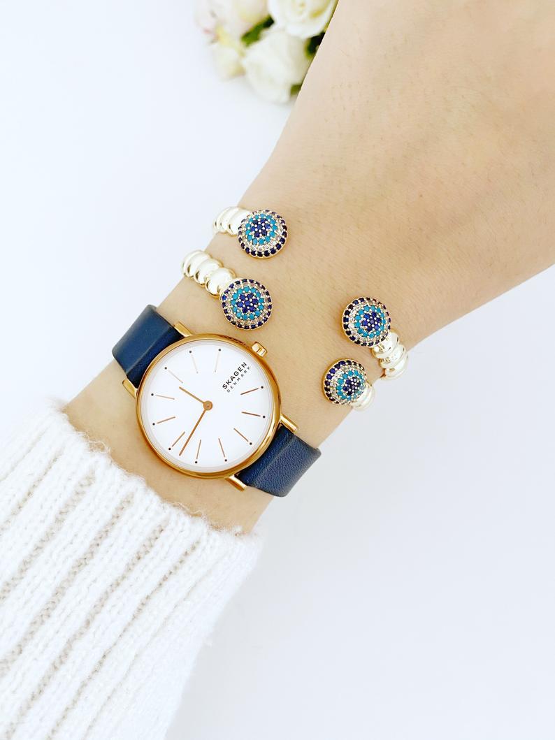 Luxury Evil Eye Bracelet featuring a gold twisted cuff and a movable zircon evil eye charm, showcasing its elegant design and adjustable fit.