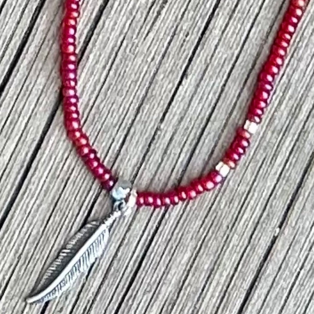 Magenta and silver seed bead necklace featuring a silver feather charm, showcasing vibrant colors and Boho style.