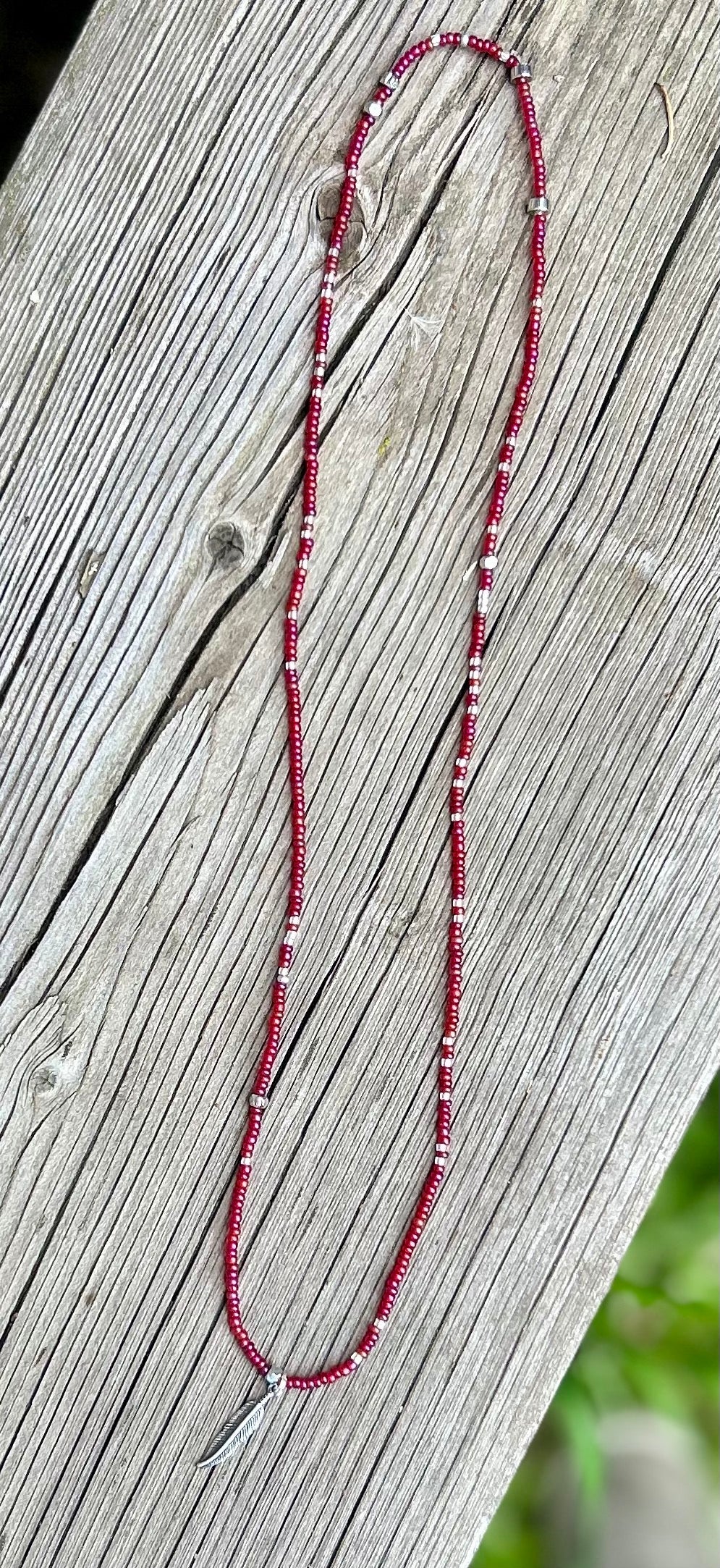Magenta and silver seed bead necklace featuring a silver feather charm, showcasing vibrant colors and Boho style.