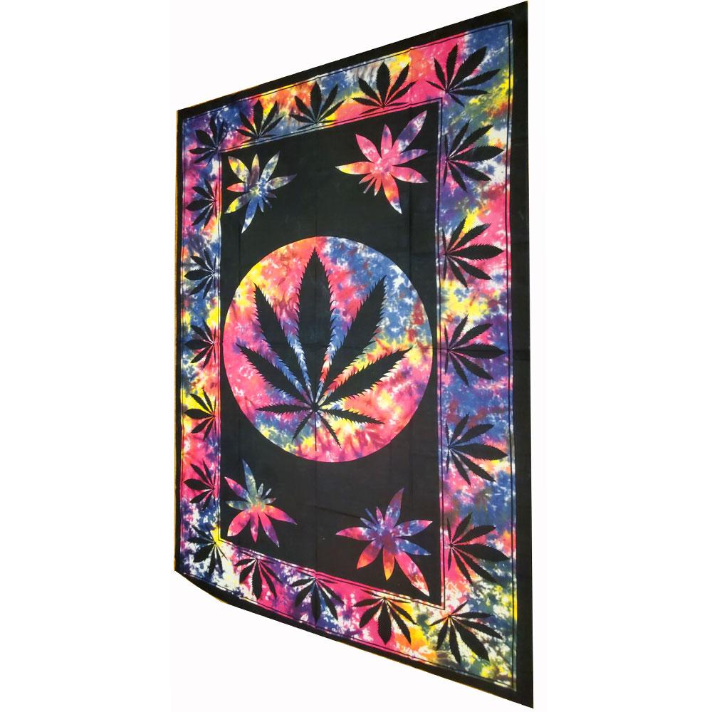 A large twin size tapestry featuring a marijuana leaf design, framed and displayed in a cozy room setting, showcasing its vibrant colors.