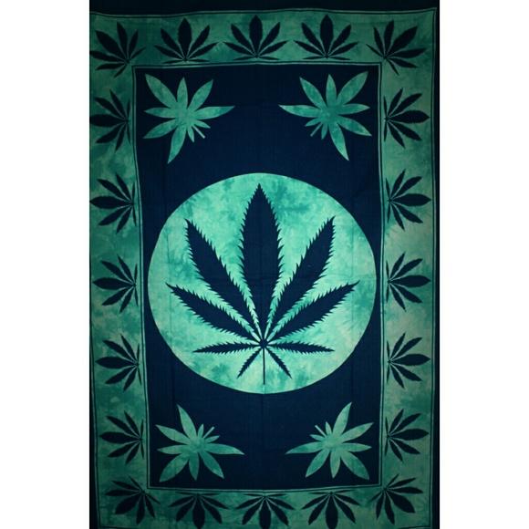 A large twin size tapestry featuring a marijuana leaf design, framed and displayed in a cozy room setting, showcasing its vibrant colors.