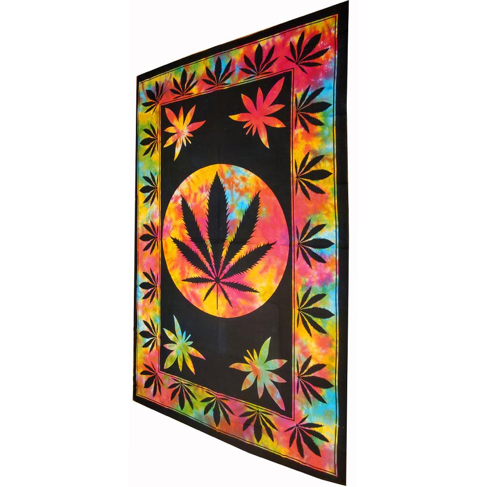 A large twin size tapestry featuring a marijuana leaf design, framed and displayed in a cozy room setting, showcasing its vibrant colors.