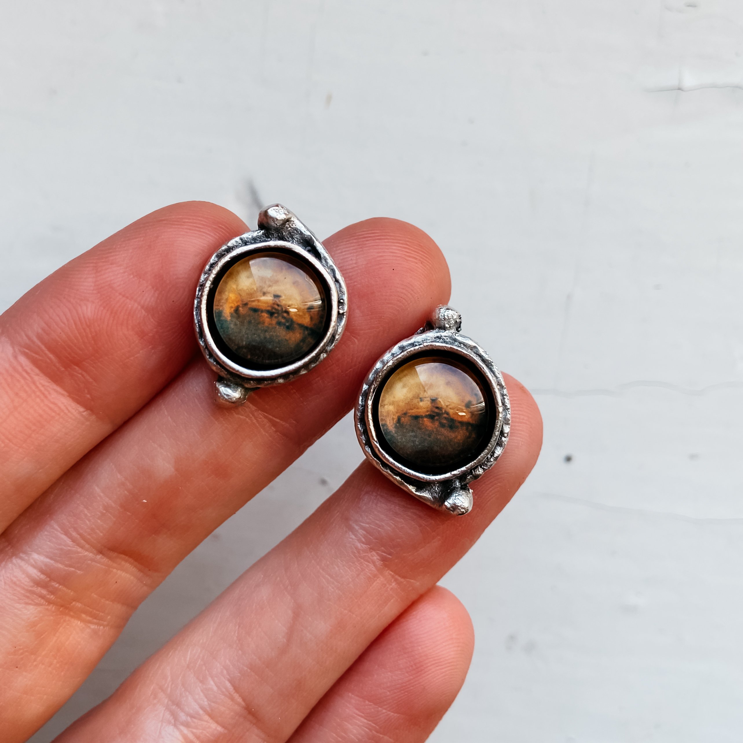 A pair of handcrafted Mars and Moons Earrings featuring the red planet Mars with silver beads representing its moons, Deimos and Phobos.