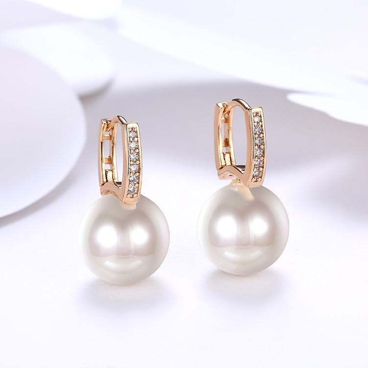 Micro-Pav'e Austrian Crystal Curved Pearl Huggie Earrings set in 18K gold, showcasing their elegant design and sparkling crystals.