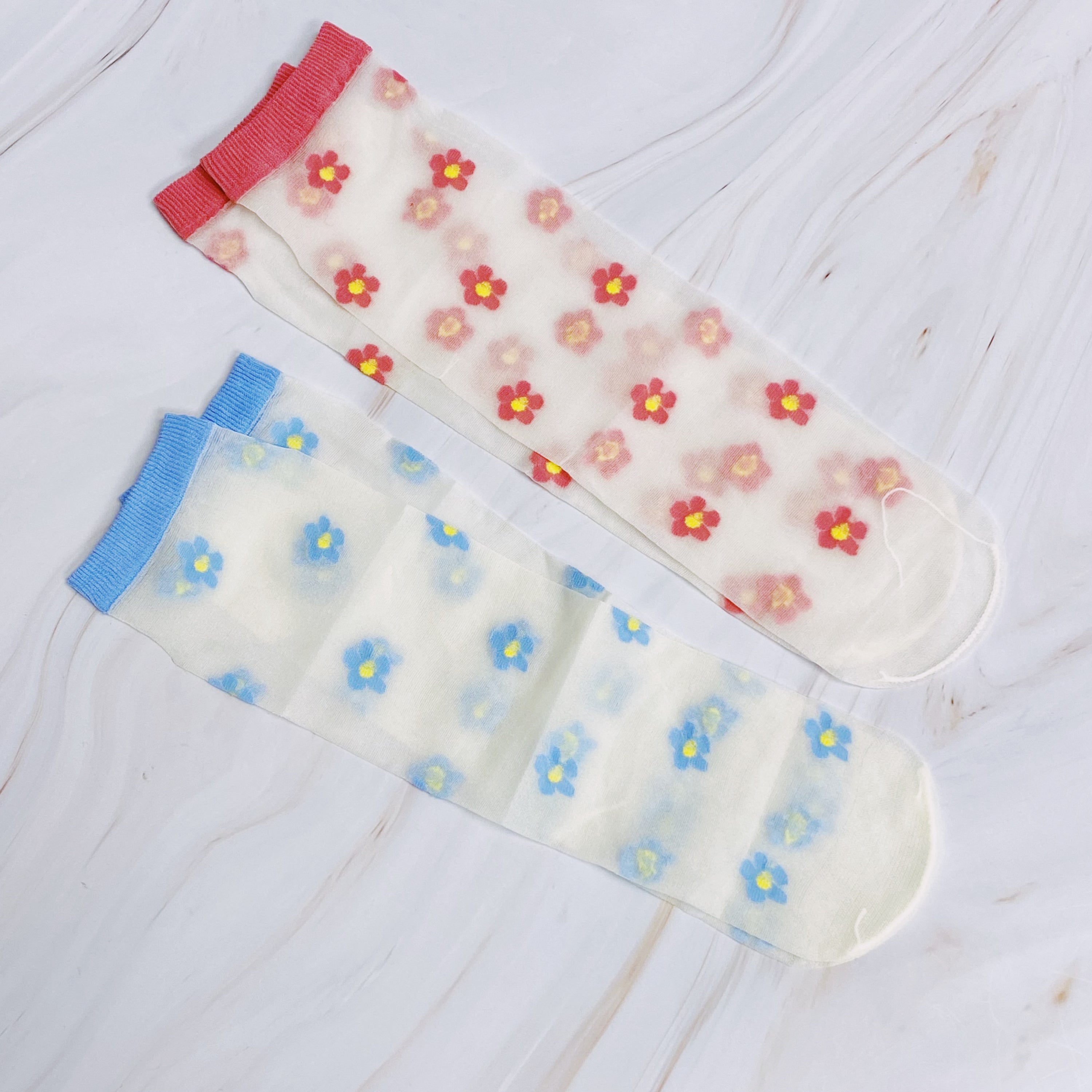 A set of two pairs of mini flower sheer socks, featuring a delicate floral design on a lightweight sheer fabric.