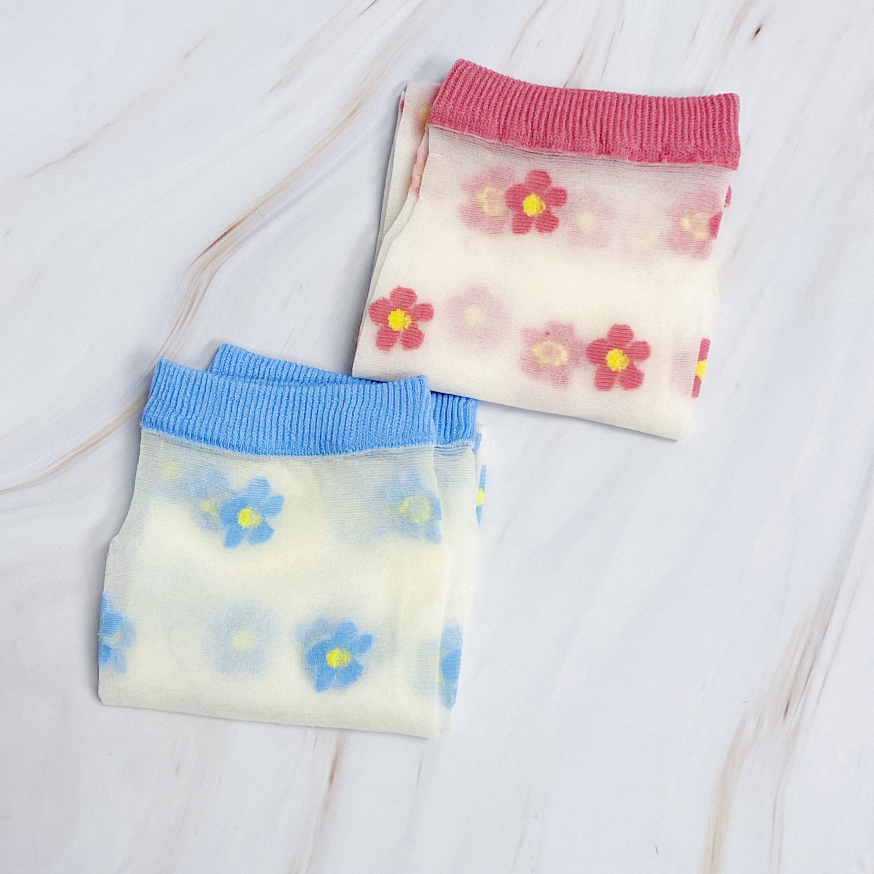 A set of two pairs of mini flower sheer socks, featuring a delicate floral design on a lightweight sheer fabric.
