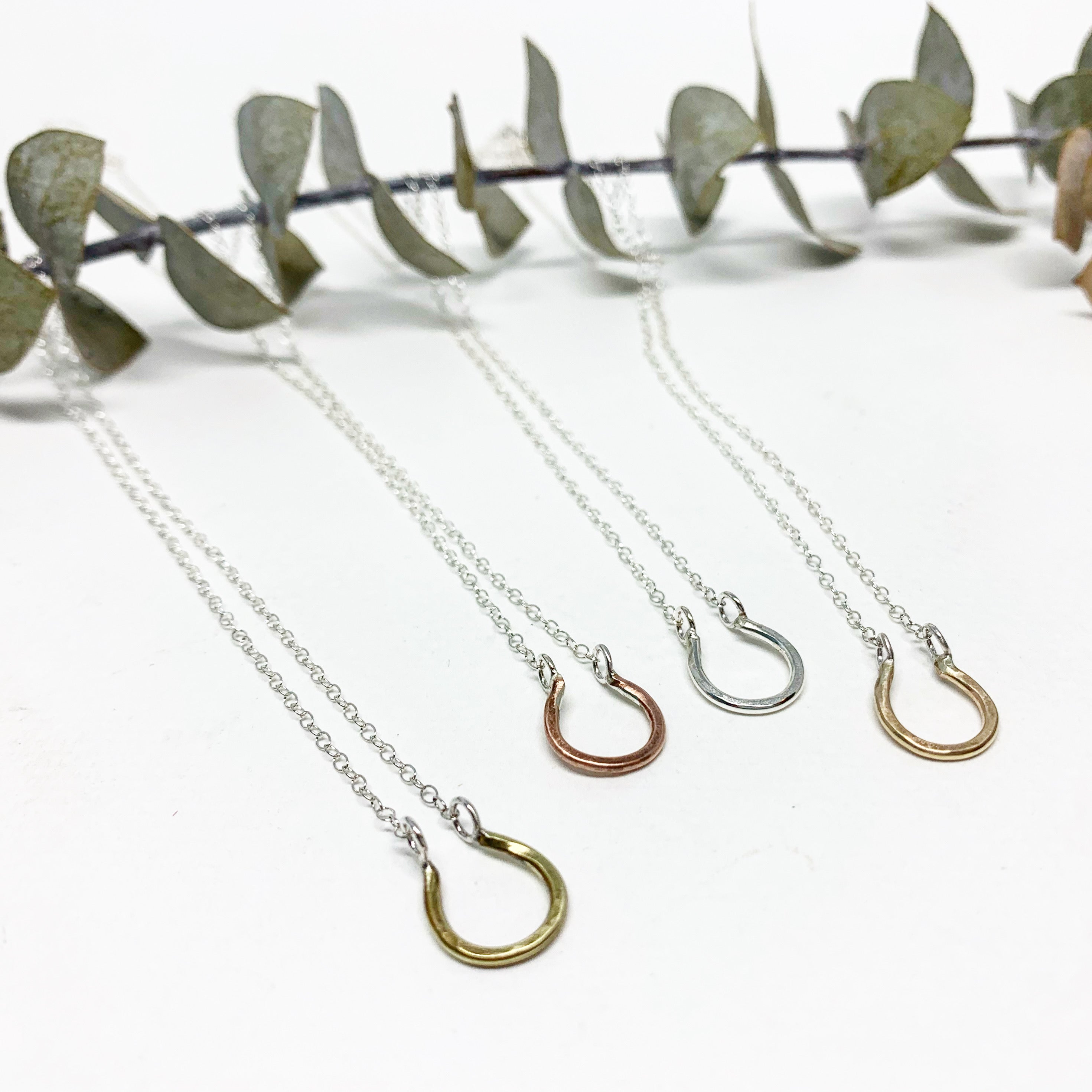 A handmade Mini Lucky Horseshoe Charm Necklace featuring a rustic, lightly hammered horseshoe charm on an adjustable chain.