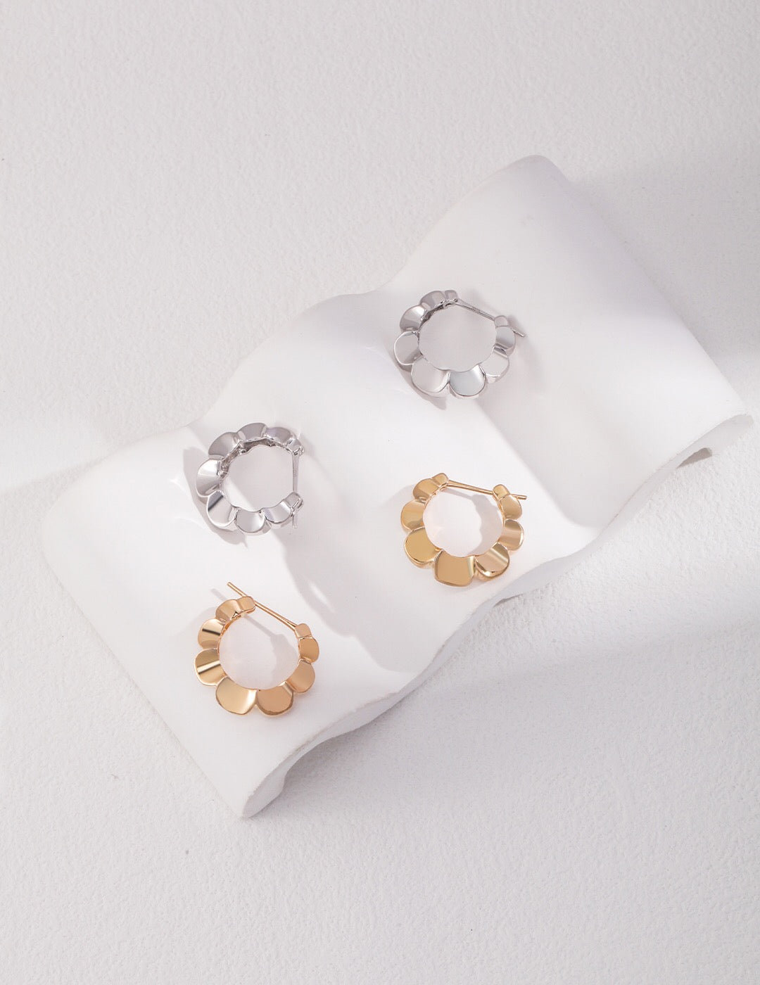 A pair of elegant Minimalist Petal Hoop Earrings made from sterling silver with a gold vermeil finish, showcasing their delicate petal design.
