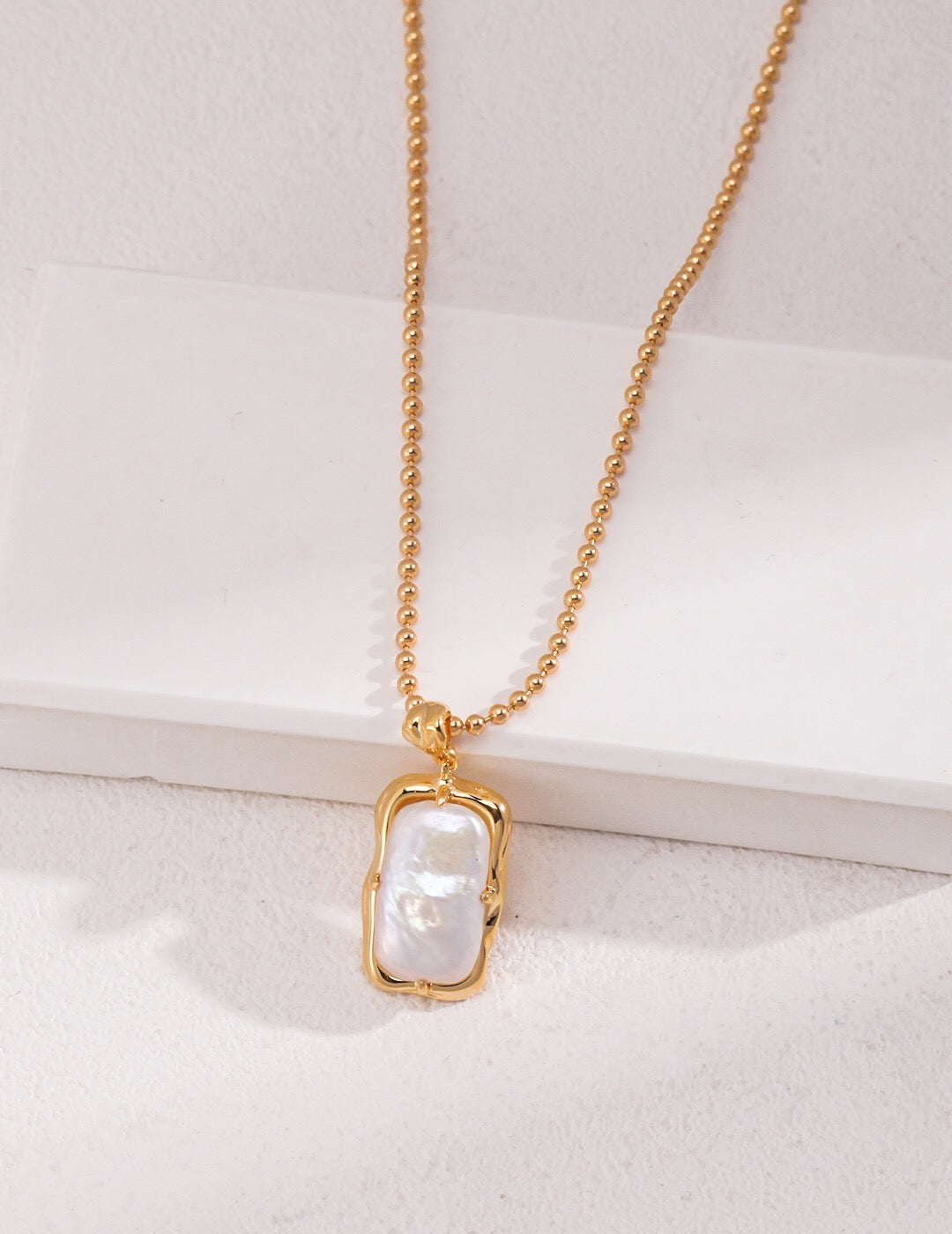 A delicate Minimalist Rectangle Pearl Necklace featuring natural pearls and gold vermeil, elegantly displayed on a soft fabric background.