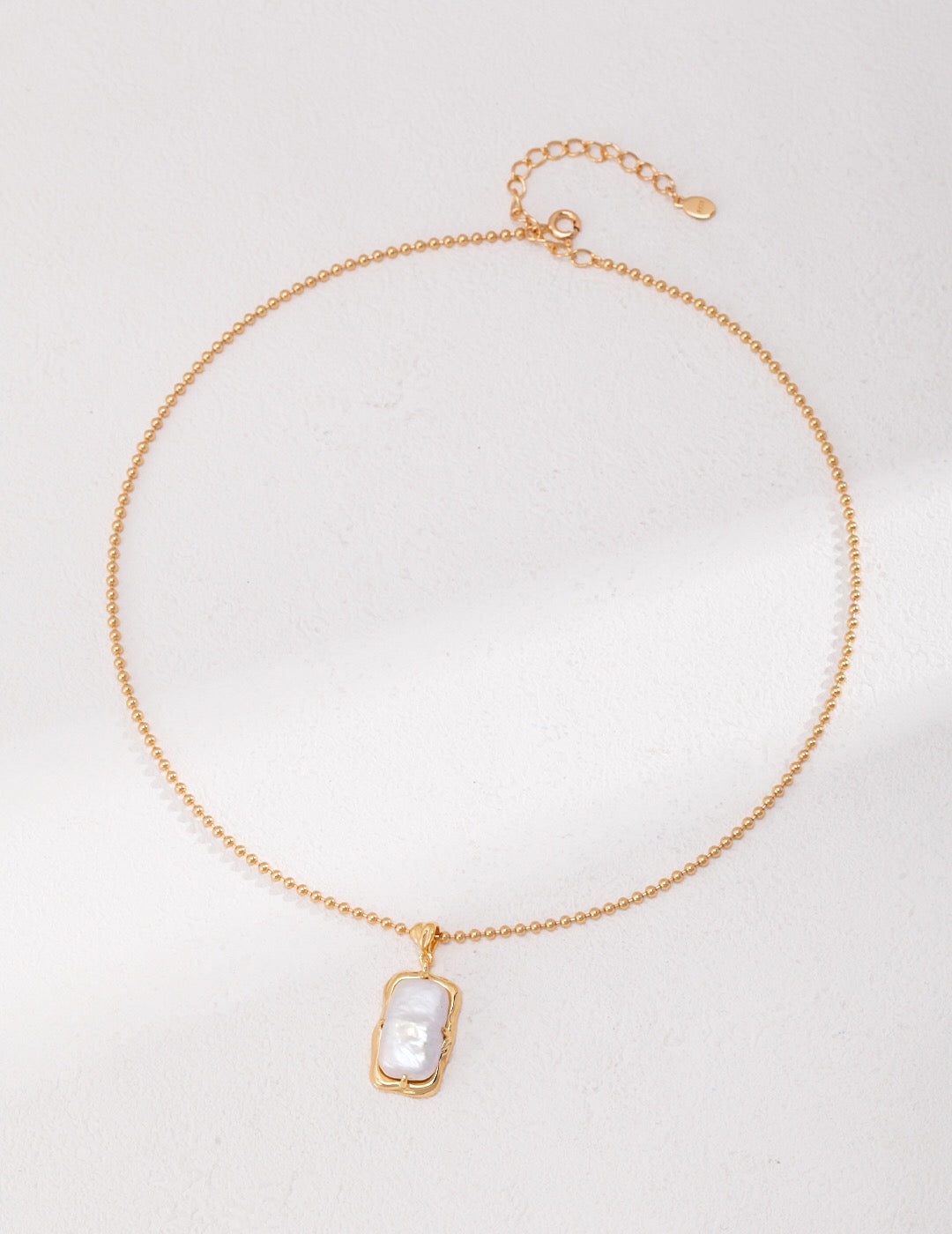 A delicate Minimalist Rectangle Pearl Necklace featuring natural pearls and gold vermeil, elegantly displayed on a soft fabric background.