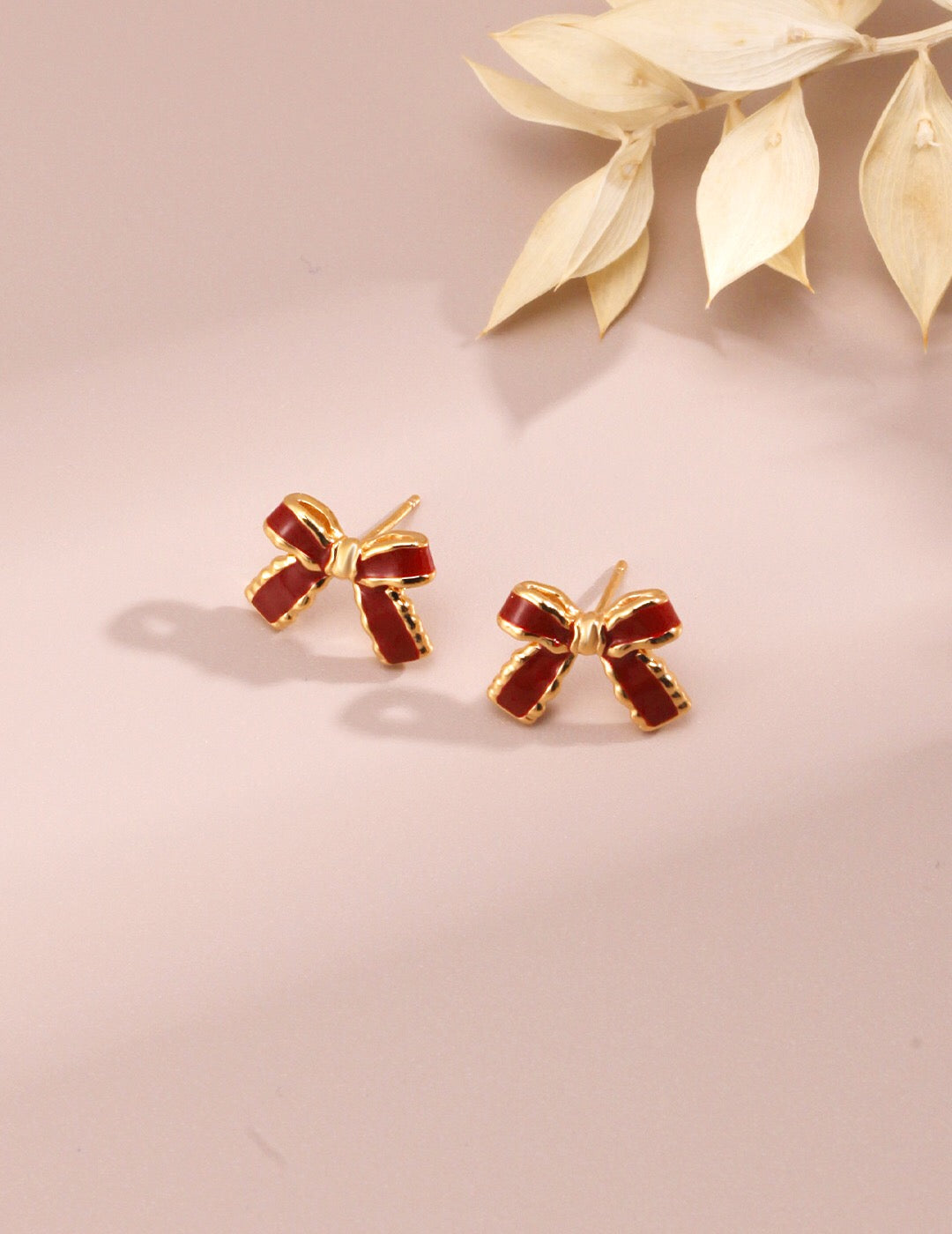 Minimalist Red Glaze Ribbon Stud earrings featuring a vibrant red glaze, crafted from sterling silver and gold vermeil, elegantly displayed in a jewelry pouch.