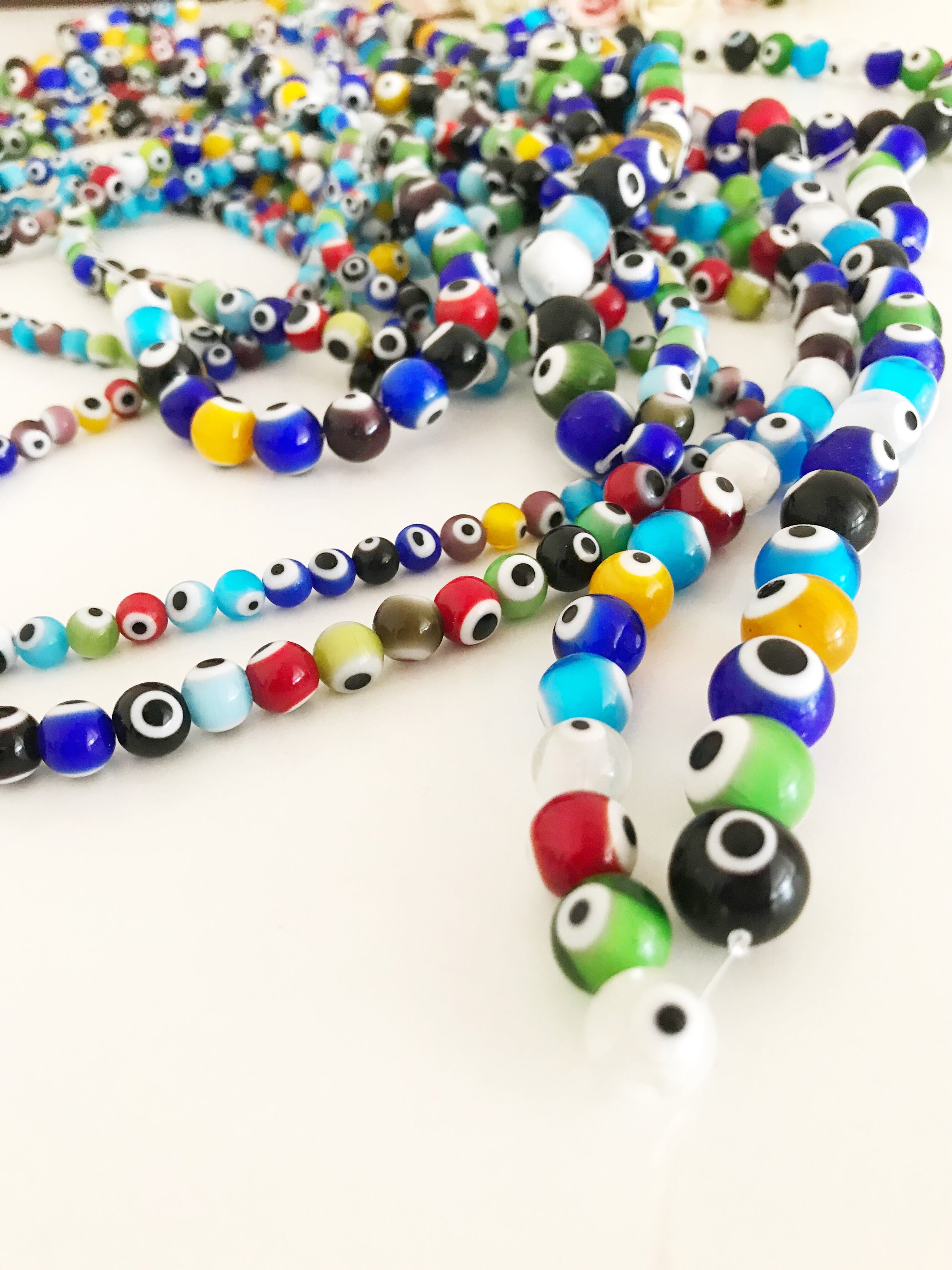 A collection of vibrant mix color evil eye beads ranging from 6mm to 12mm, showcasing their round glass design and protective symbolism.