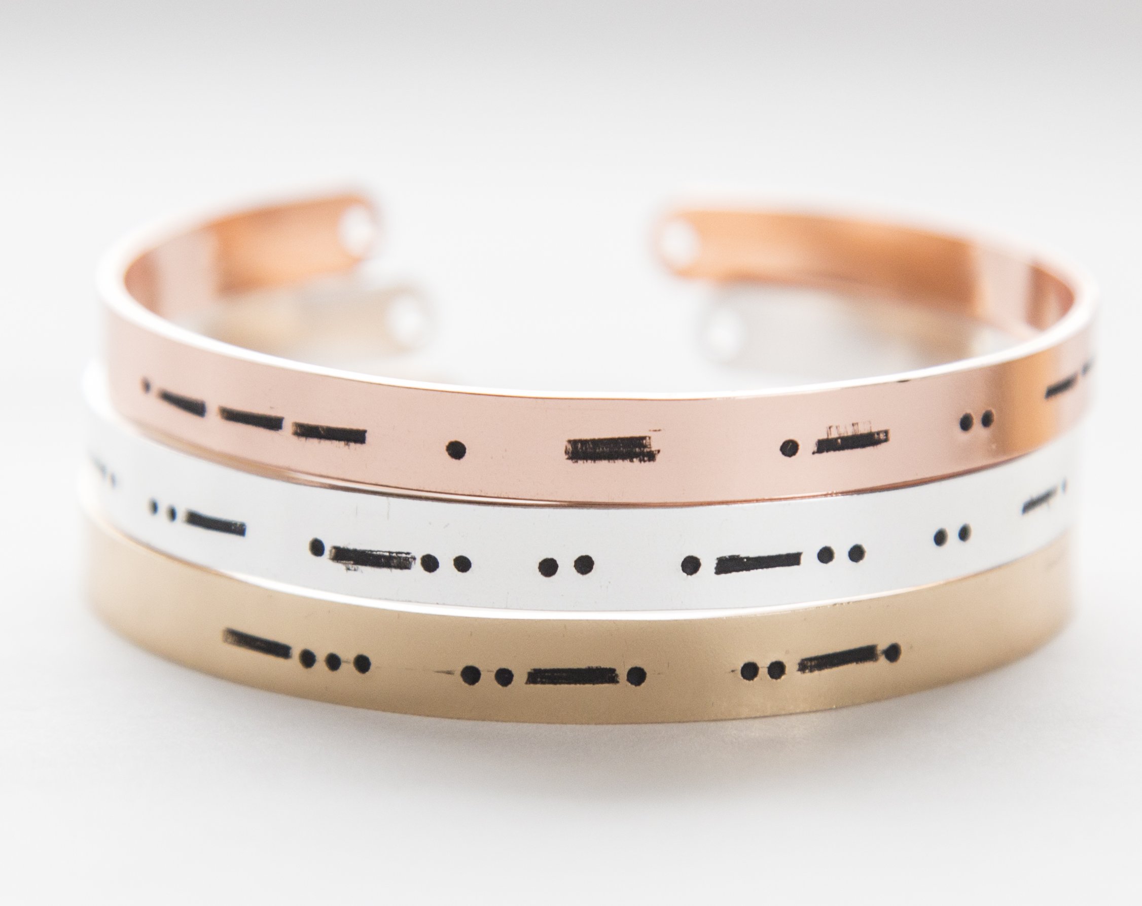 A stylish Morse code bracelet made of copper with rose gold plating, featuring hand-stamped letters and an adjustable design.