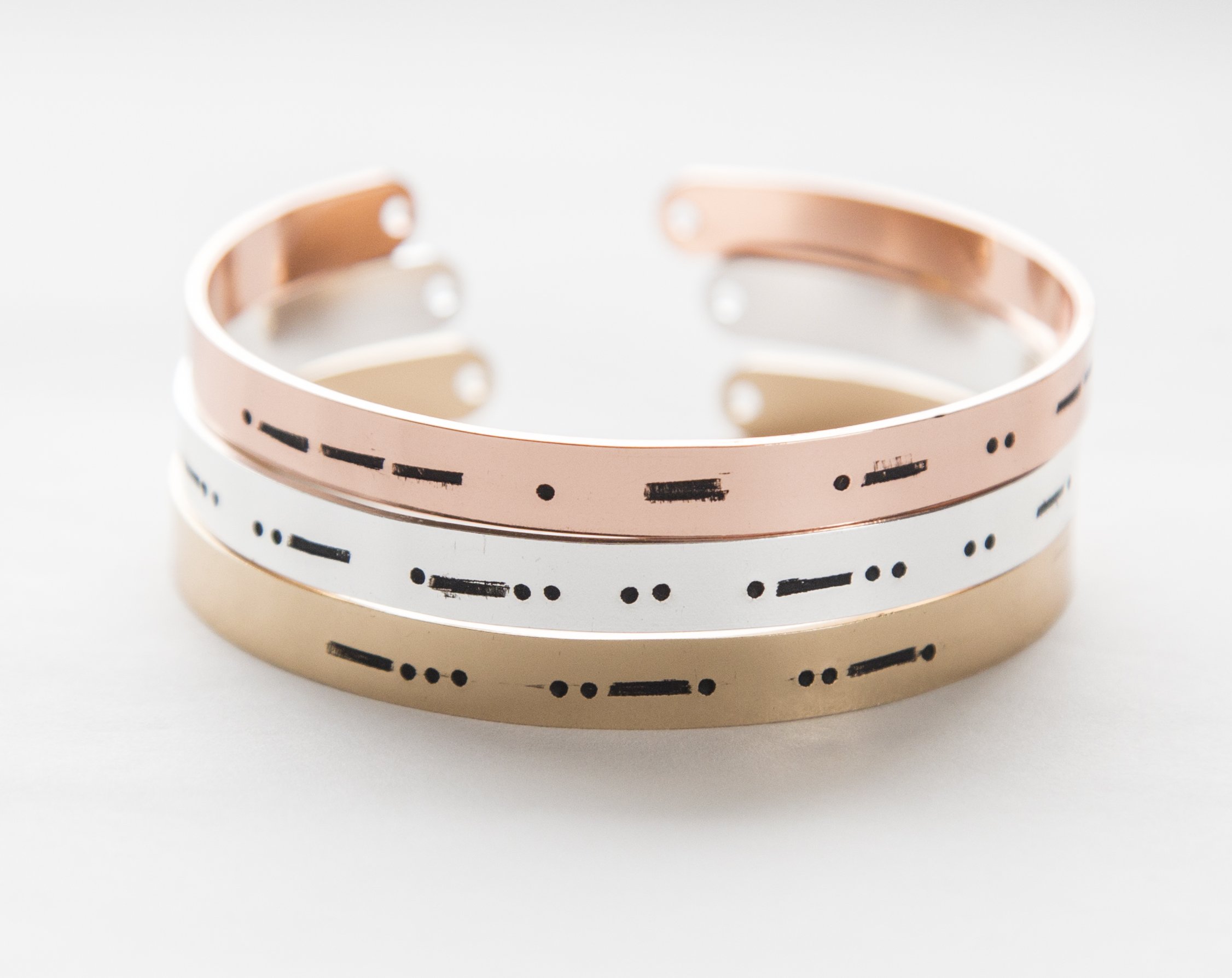 A stylish Morse code bracelet made of copper with rose gold plating, featuring hand-stamped letters and an adjustable design.