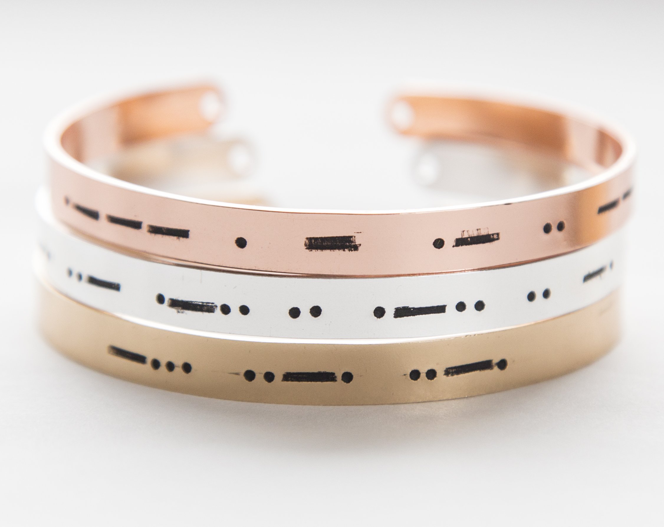 A stylish Morse code bracelet made of copper with rose gold plating, featuring hand-stamped letters and an adjustable design.