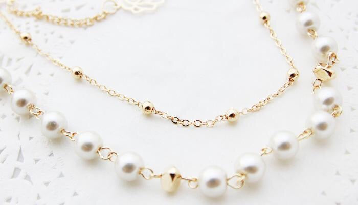 Multi-layer pearl necklace adorned with roses and rhinestones, showcasing elegance and sophistication.