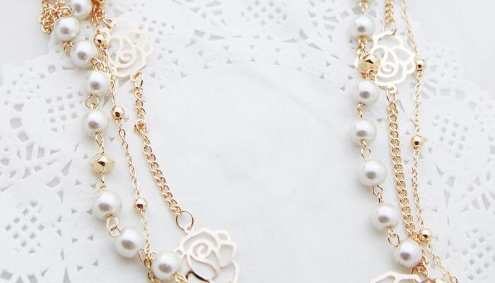 Multi-layer pearl necklace adorned with roses and rhinestones, showcasing elegance and sophistication.