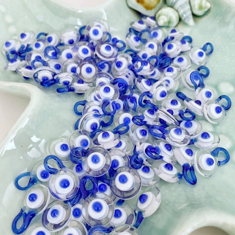 A collection of 100 Murano Evil Eye Beads in clear and blue colors, showcasing their intricate designs and craftsmanship.