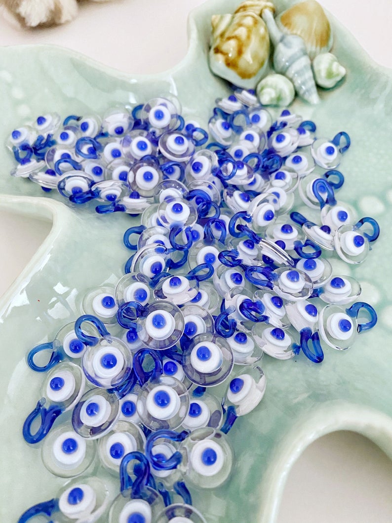 A collection of 100 Murano Evil Eye Beads in clear and blue colors, showcasing their intricate designs and craftsmanship.