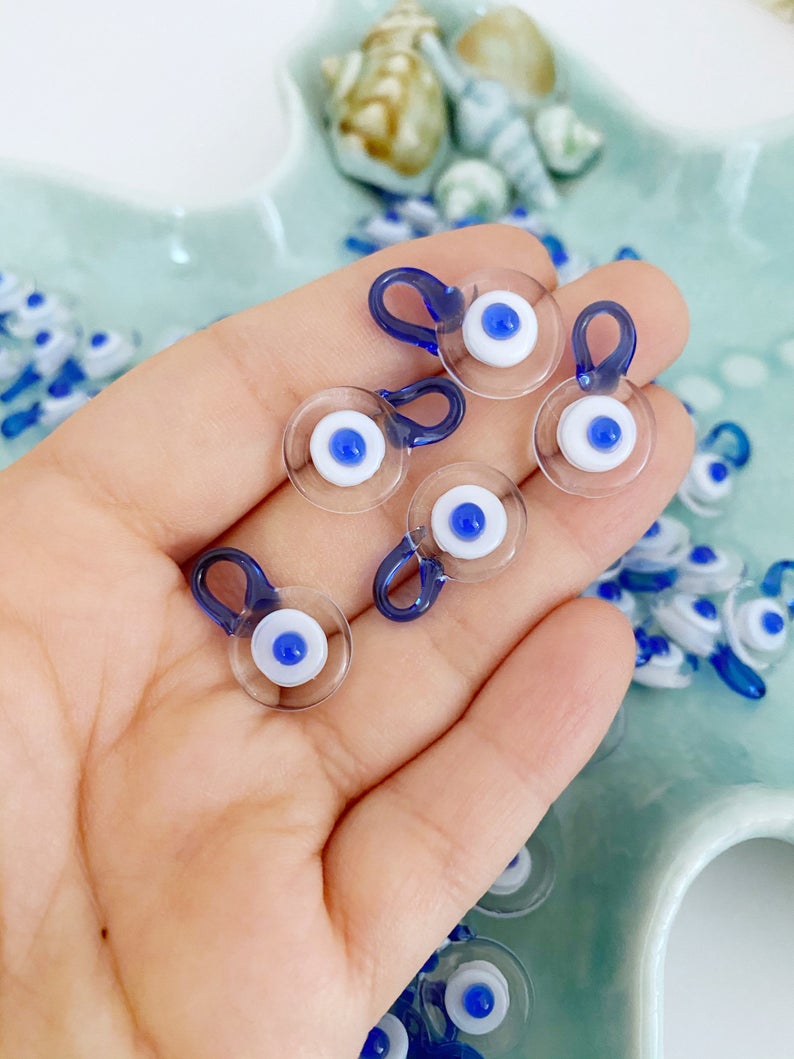 A collection of 100 Murano Evil Eye Beads in clear and blue colors, showcasing their intricate designs and craftsmanship.