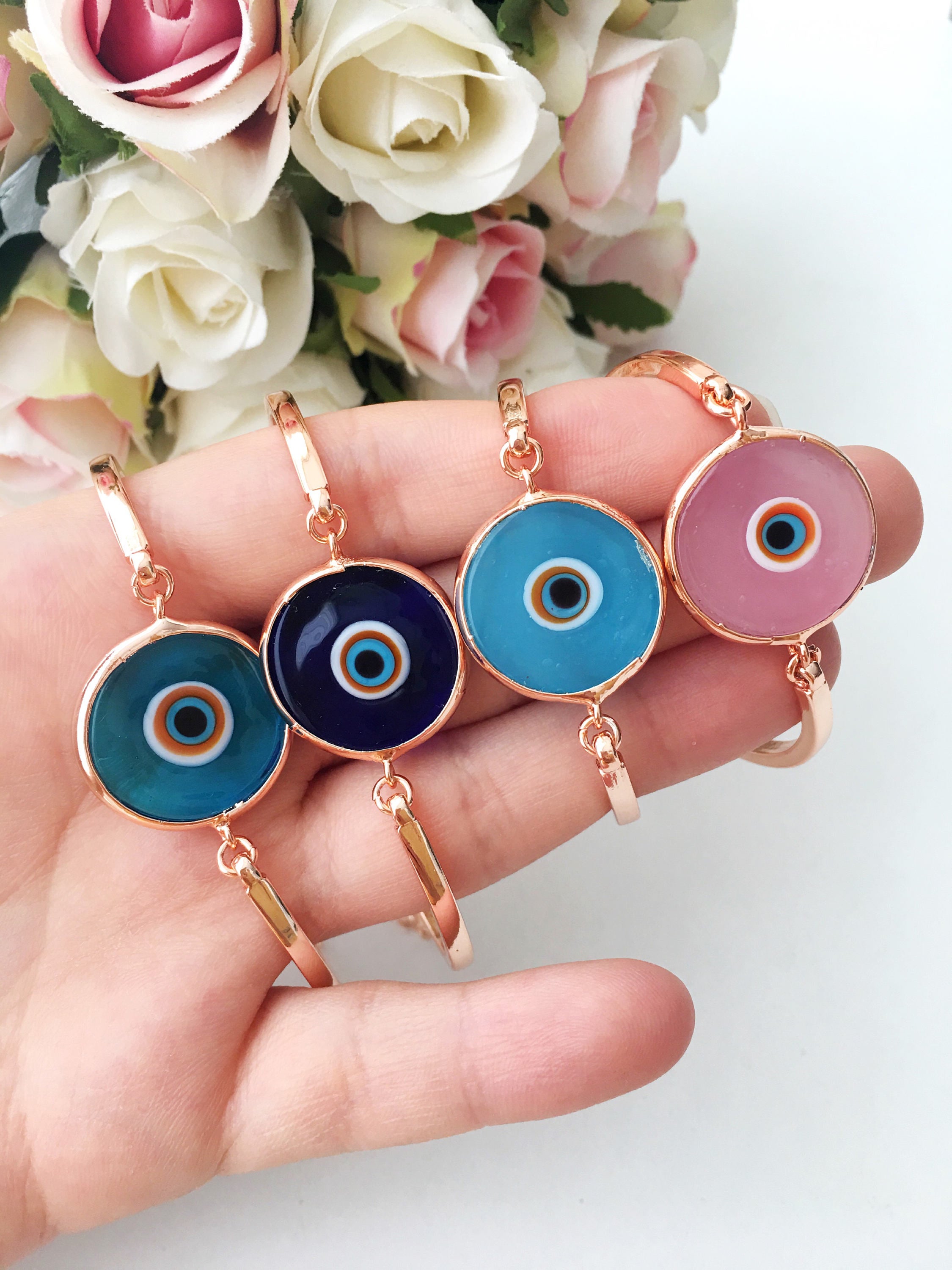 A collection of Murano Evil Eye Charm Bracelets in various colors including dark blue, baby blue, turquoise, baby pink, and white, showcasing their unique glass charms.
