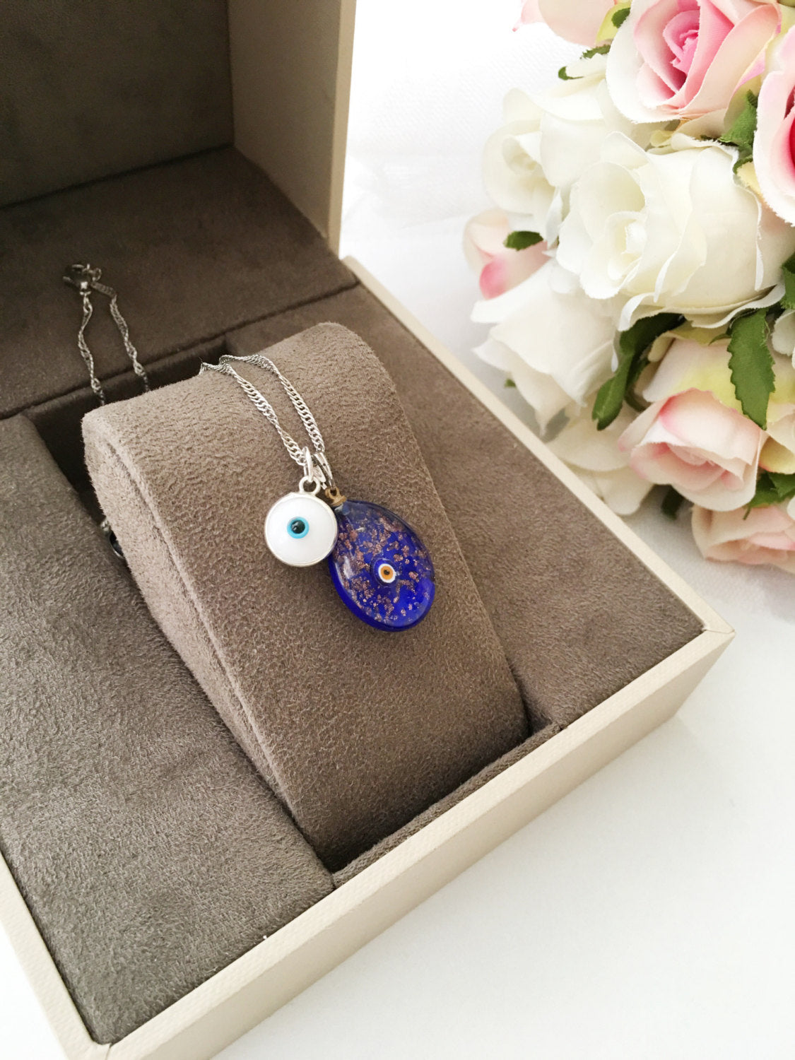 Murano Glass Evil Eye Necklace featuring a large blue evil eye bead and tiny white and dark blue beads, showcasing intricate craftsmanship.