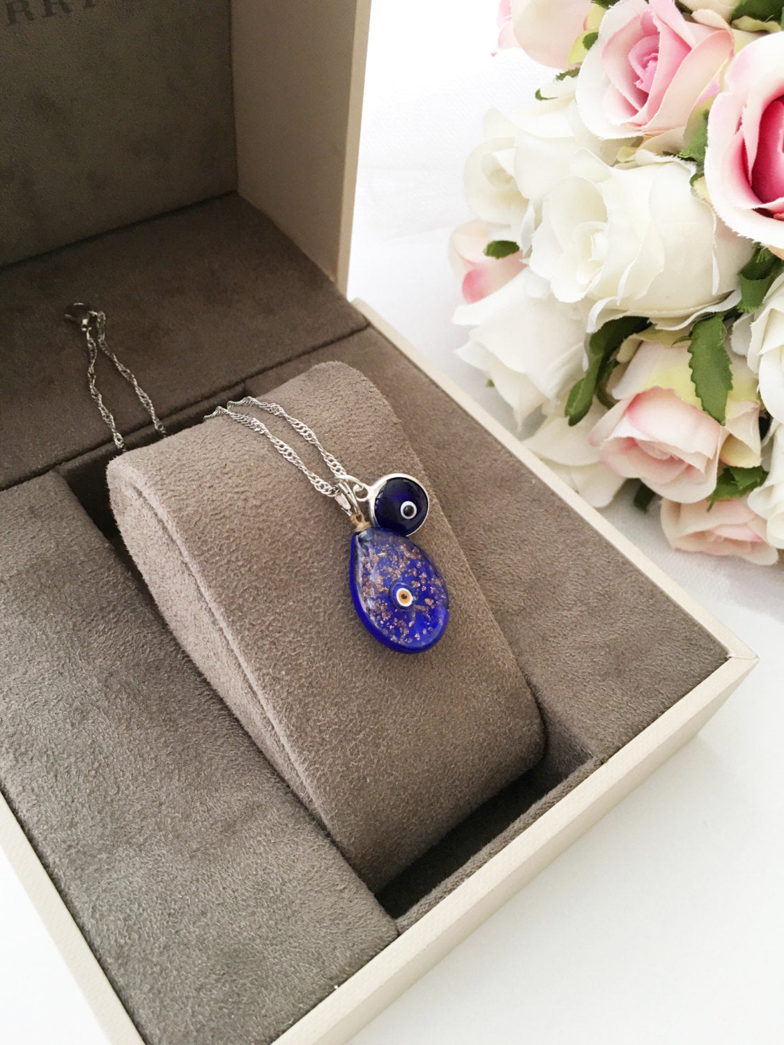 Murano Glass Evil Eye Necklace featuring a large blue evil eye bead and tiny white and dark blue beads, showcasing intricate craftsmanship.