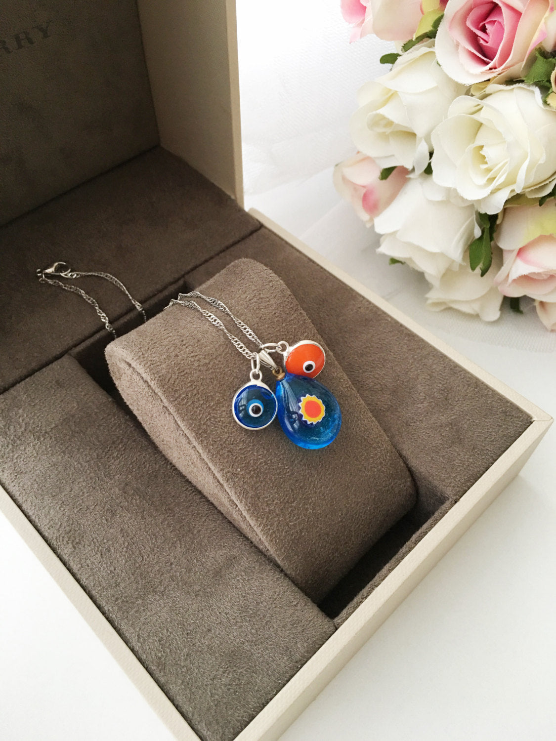 A beautifully handcrafted Murano glass evil eye necklace featuring a large central evil eye bead and smaller orange and turquoise beads.