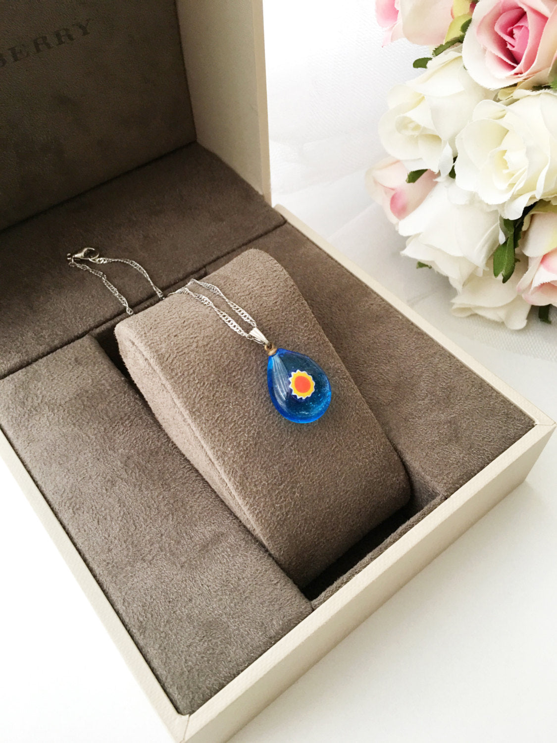 A beautifully handcrafted Murano glass evil eye necklace featuring a large central evil eye bead and smaller orange and turquoise beads.