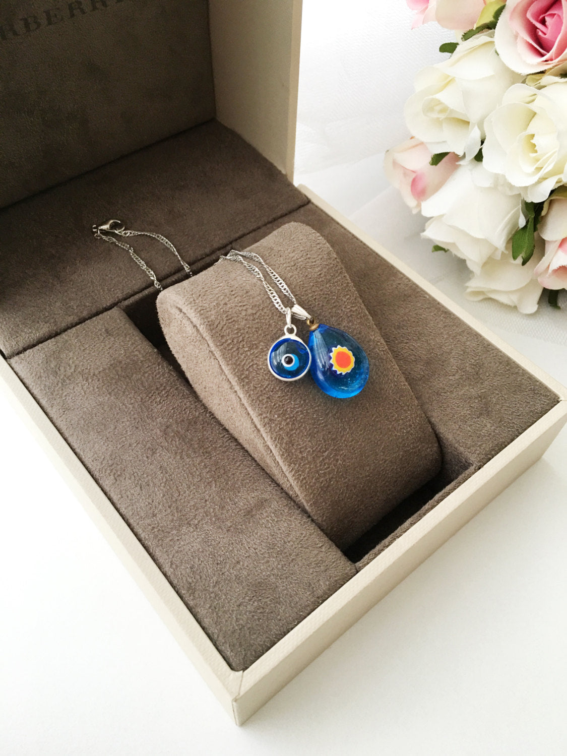 A beautifully handcrafted Murano glass evil eye necklace featuring a large central evil eye bead and smaller orange and turquoise beads.