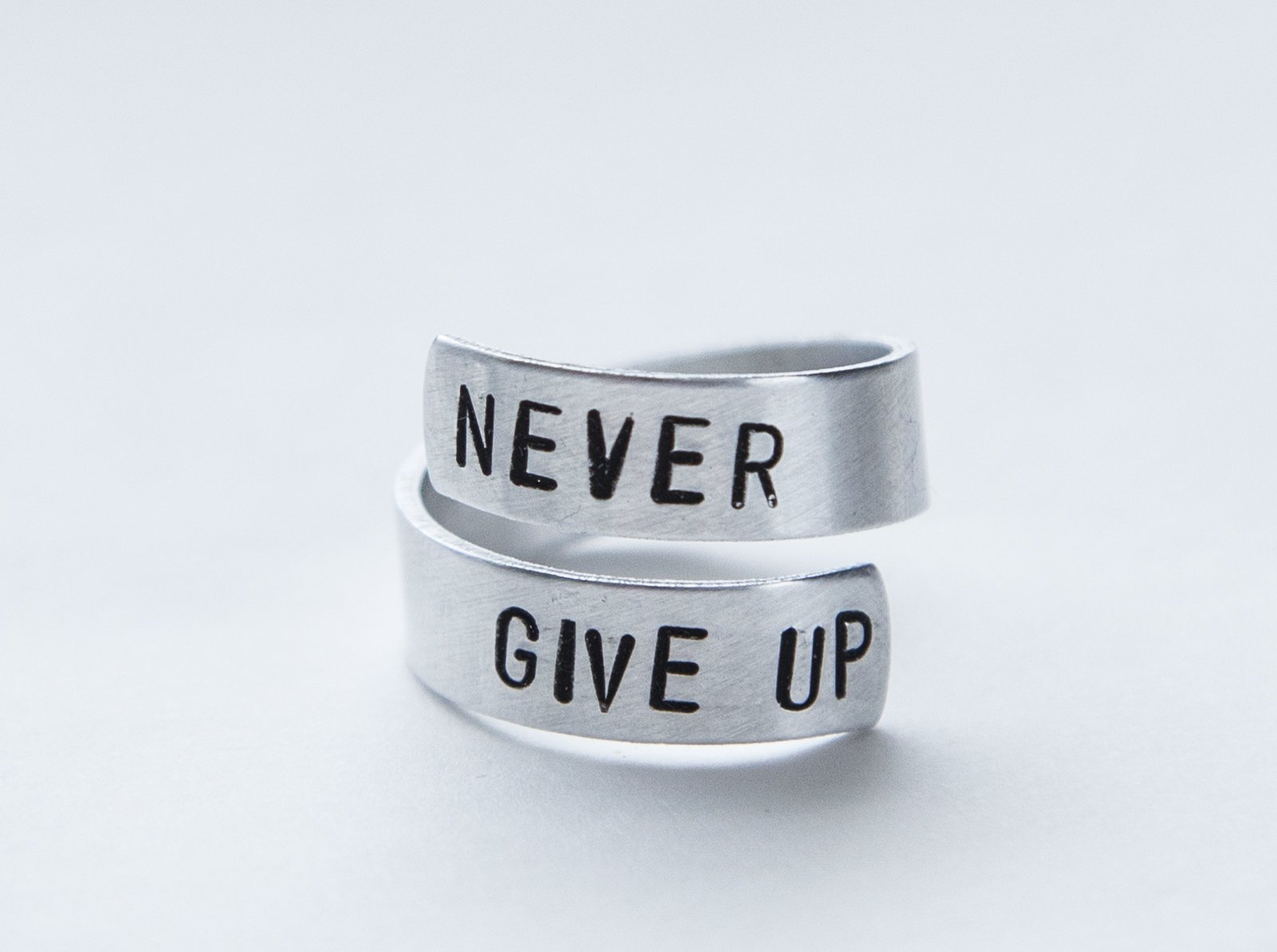 Never Fucking Give Up Ring, adjustable aluminum ring with hand-stamped letters, symbolizing cancer survival and victory.