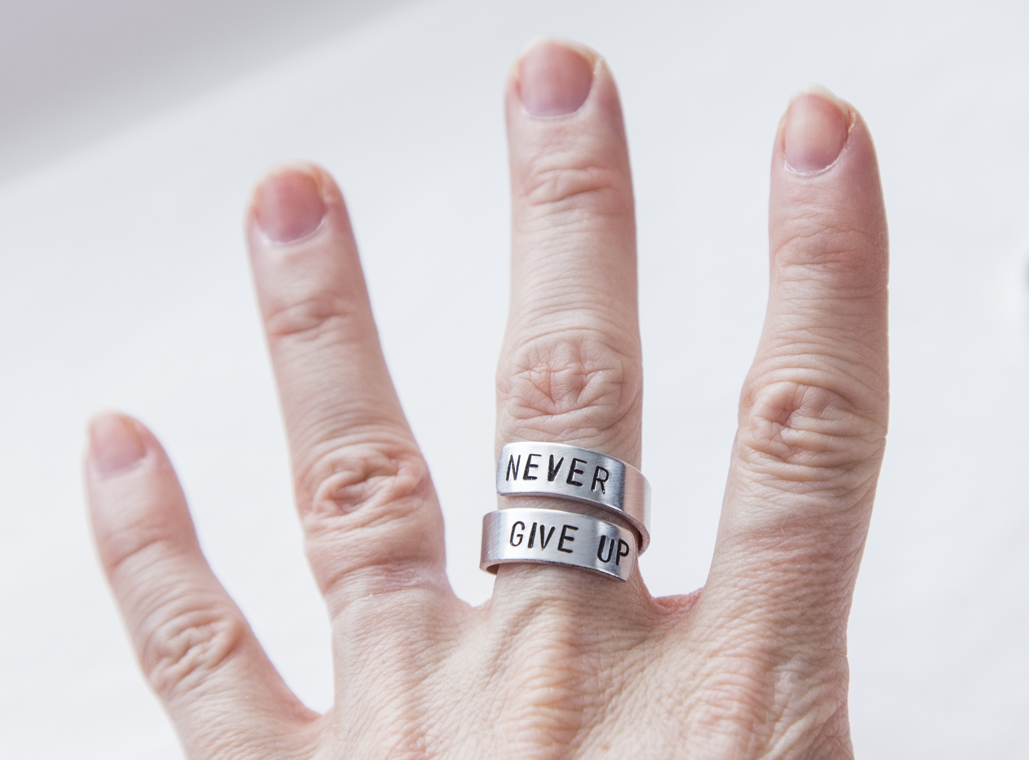 Never Fucking Give Up Ring, adjustable aluminum ring with hand-stamped letters, symbolizing cancer survival and victory.