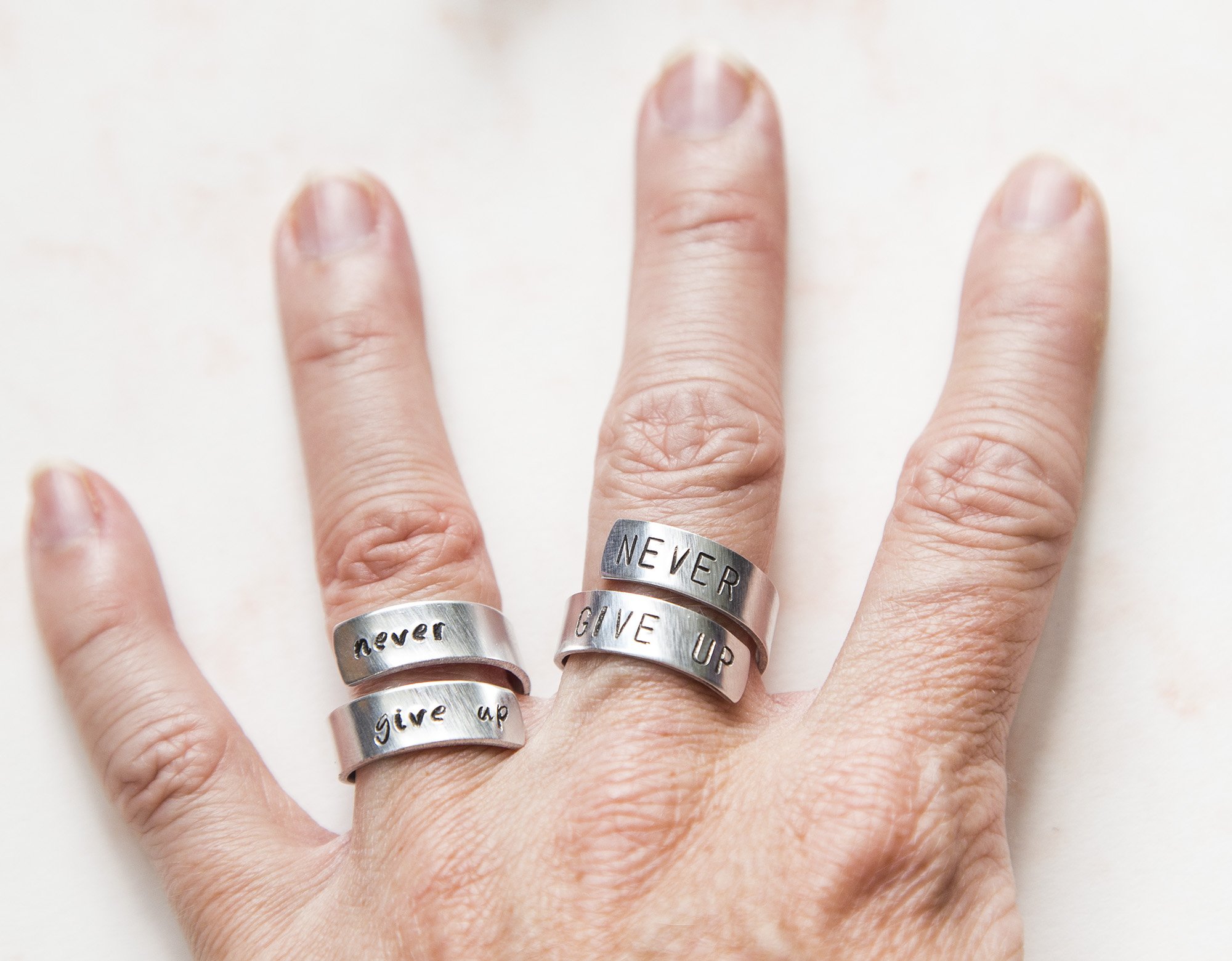 Never Fucking Give Up Ring, adjustable aluminum ring with hand-stamped letters, symbolizing cancer survival and victory.