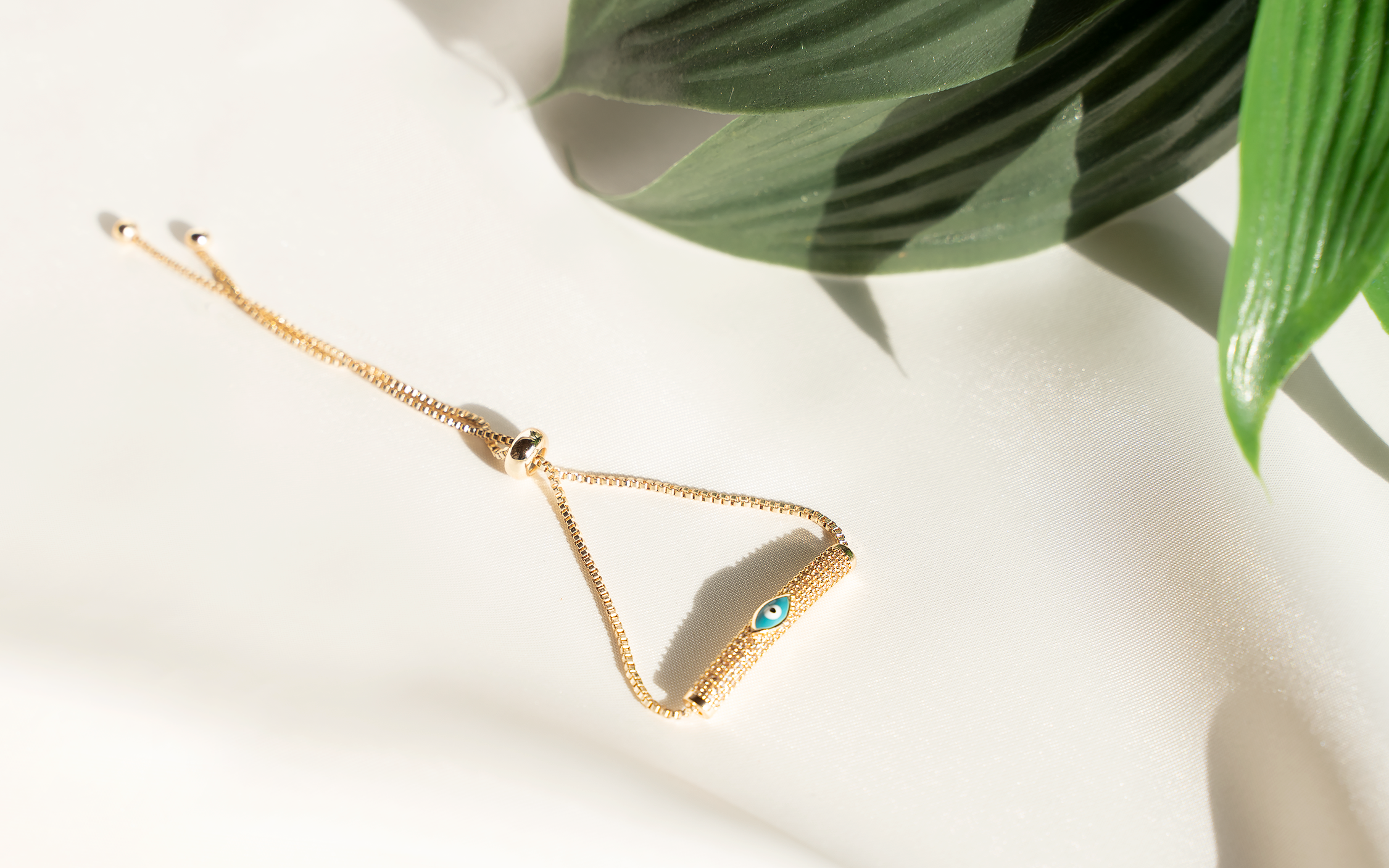 NISA Bracelet featuring an evil eye embellished cylinder bead on a gold-plated box chain, adjustable for comfort.