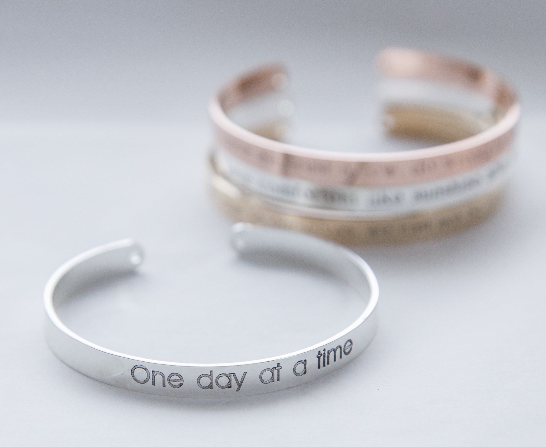 One Day at a Time Bracelet in gold, rose gold, and silver plating, showcasing its delicate design and motivational message.