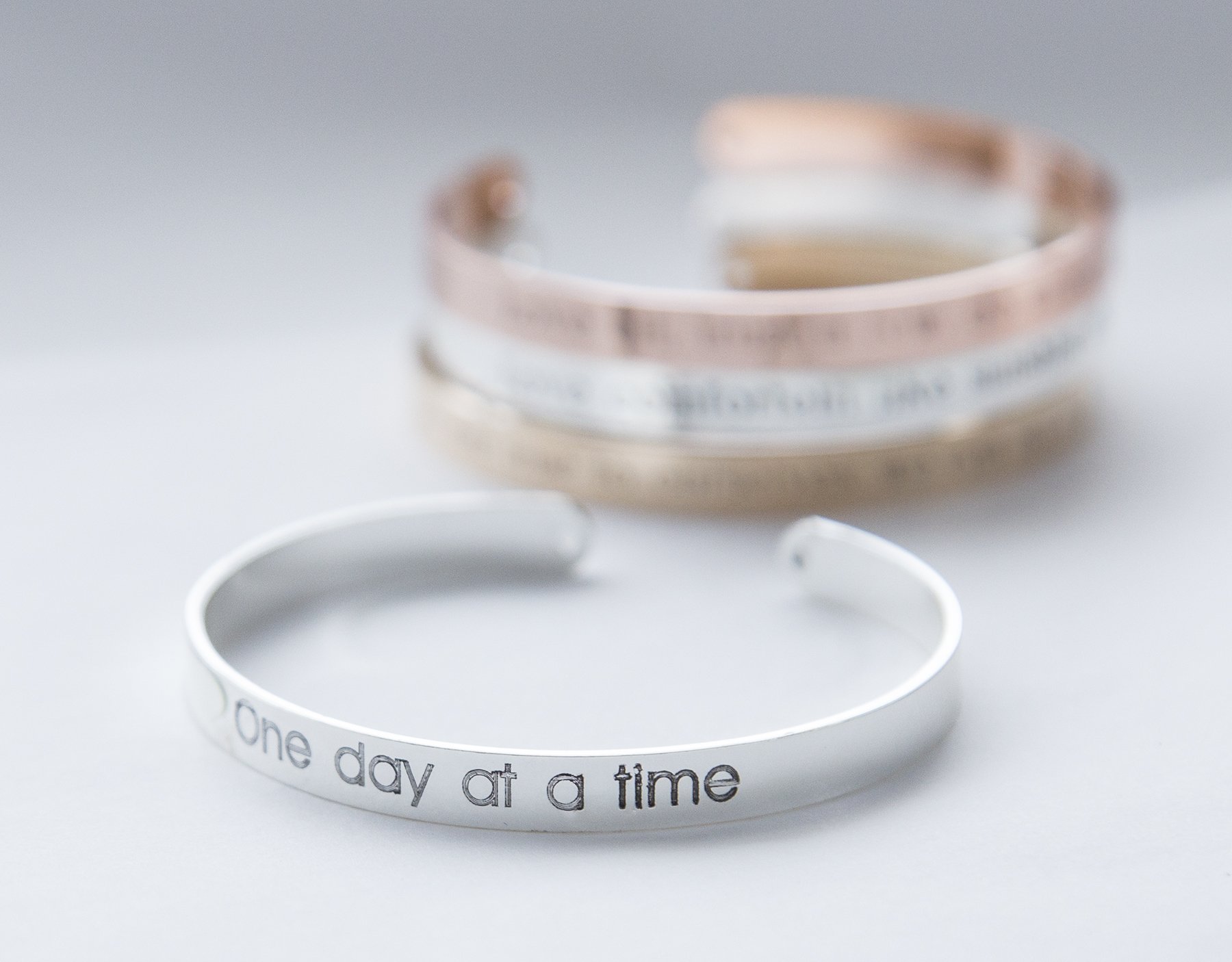 One Day at a Time Bracelet in gold, rose gold, and silver plating, showcasing its delicate design and motivational message.