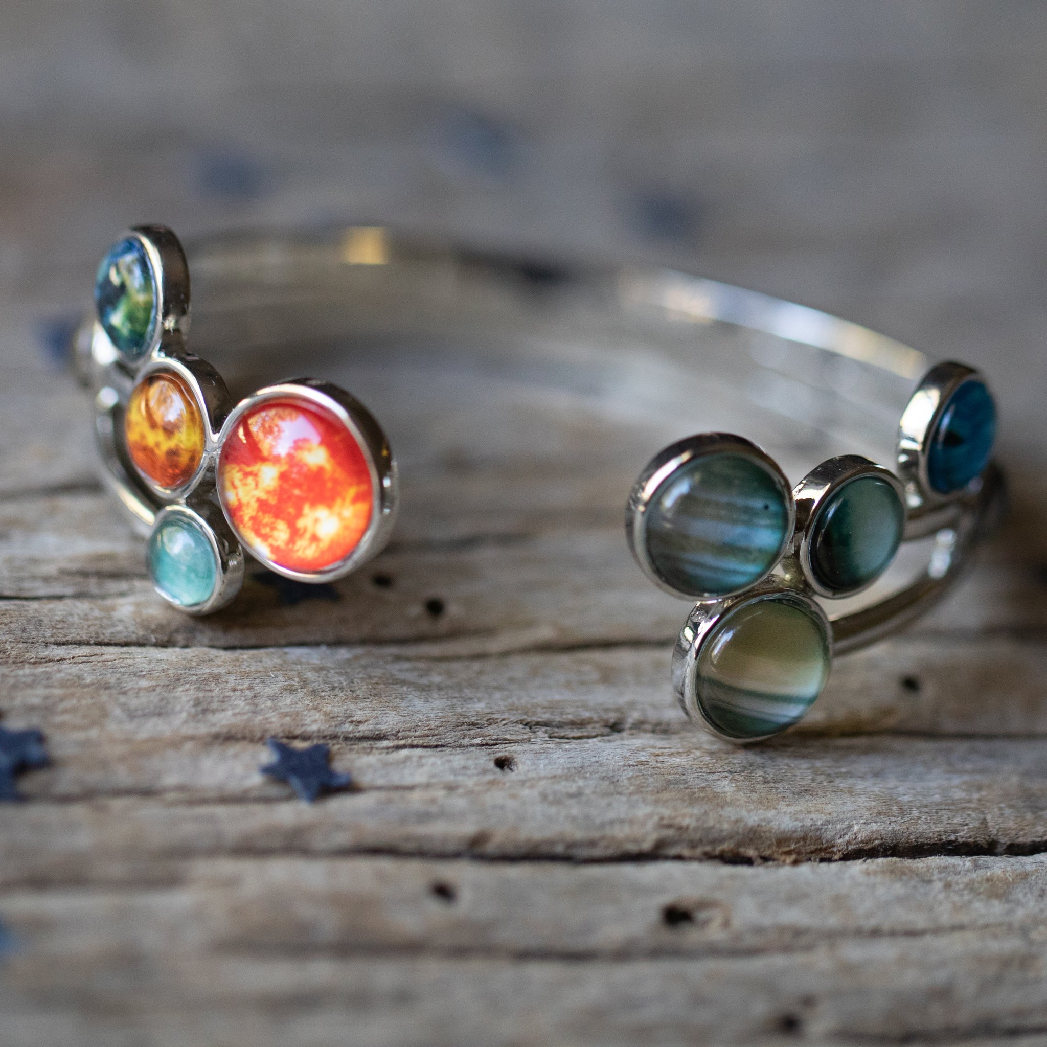 Open Solar System Cuff Bracelet featuring 9 planets and the Sun, adjustable silver-tone design, handcrafted from rhodium plated brass.