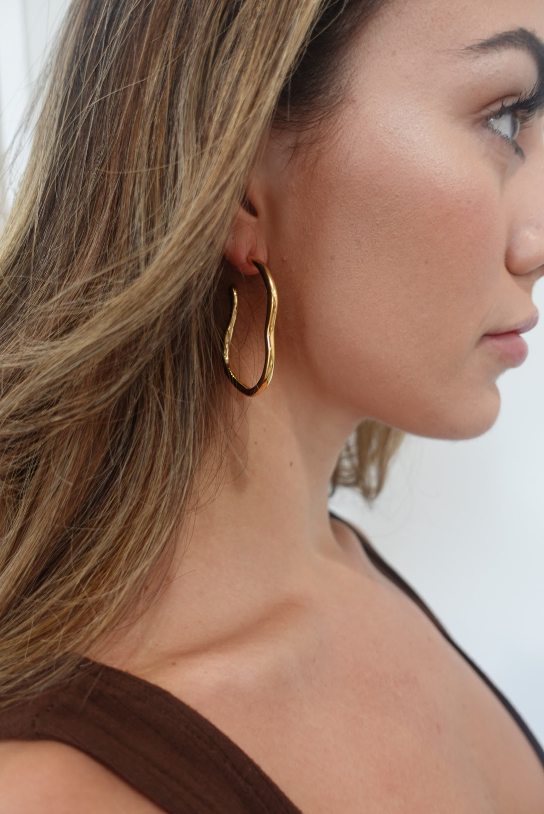 Elegant Orah Hoop earrings with a unique curved design, 18K gold plated finish, showcasing their stylish and edgy appeal.