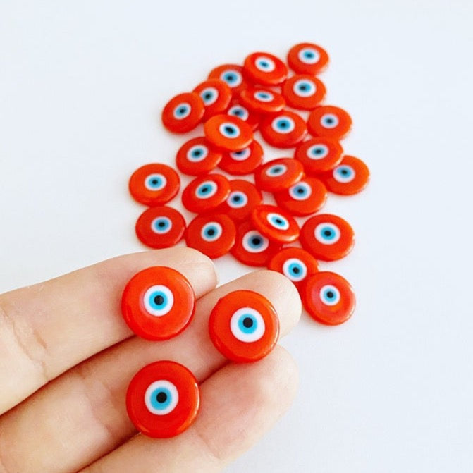 A collection of vibrant orange 15mm Murano glass cabochons featuring the evil eye design, perfect for jewelry making.