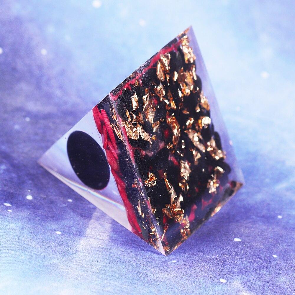 A handcrafted Orgonite pyramid made of natural obsidian, red coral, copper, and gold foil, designed for energy healing and meditation.
