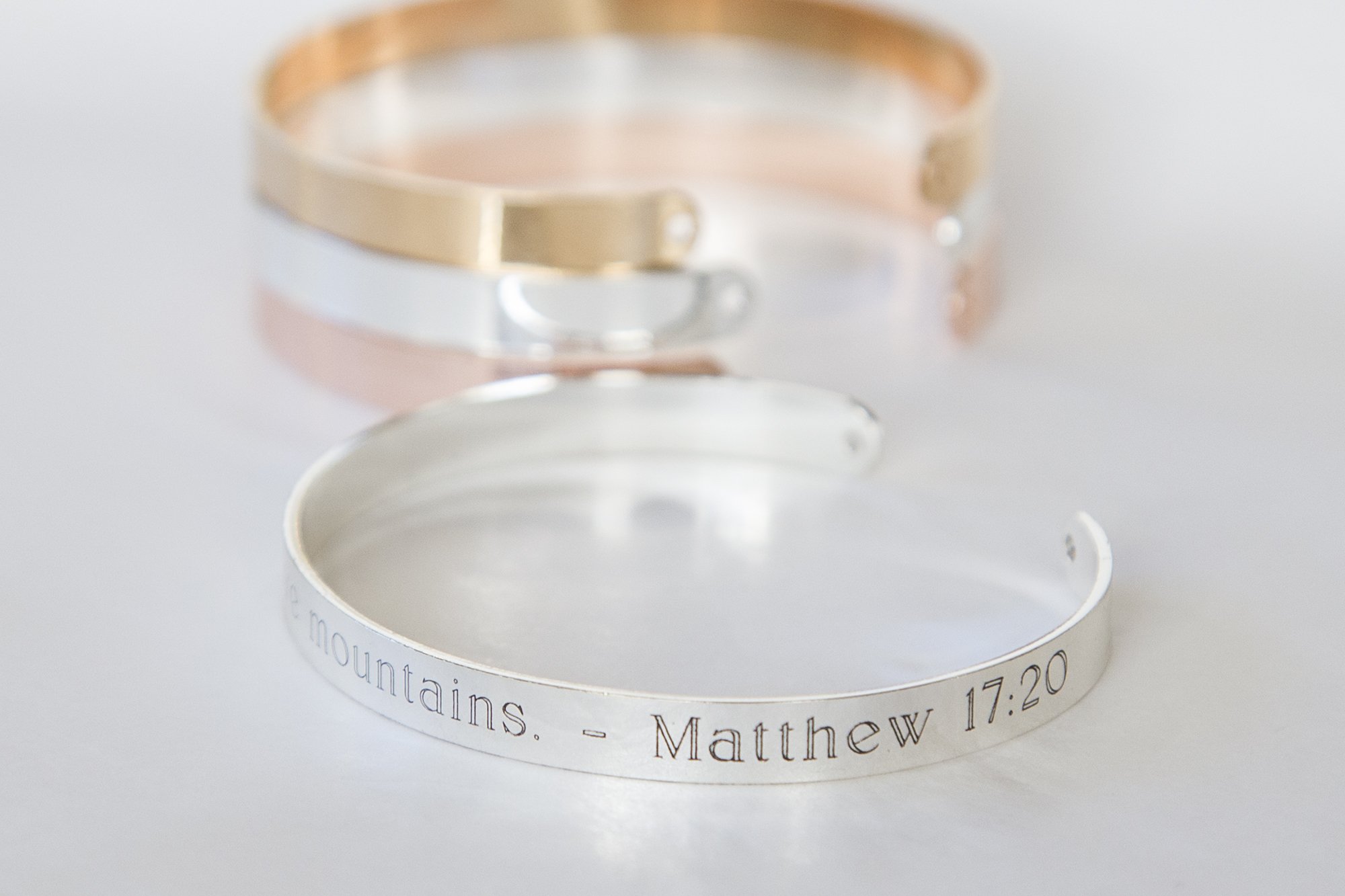 A delicate adjustable bracelet featuring the quote 'Our faith can move mountains' engraved, available in gold, rose gold, and silver finishes.
