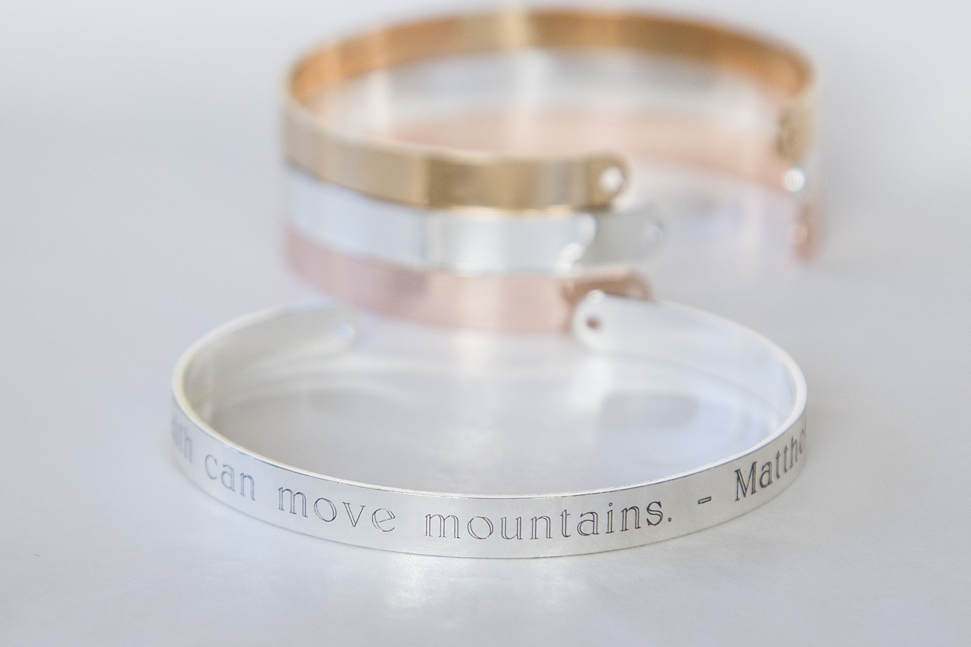 A delicate adjustable bracelet featuring the quote 'Our faith can move mountains' engraved, available in gold, rose gold, and silver finishes.