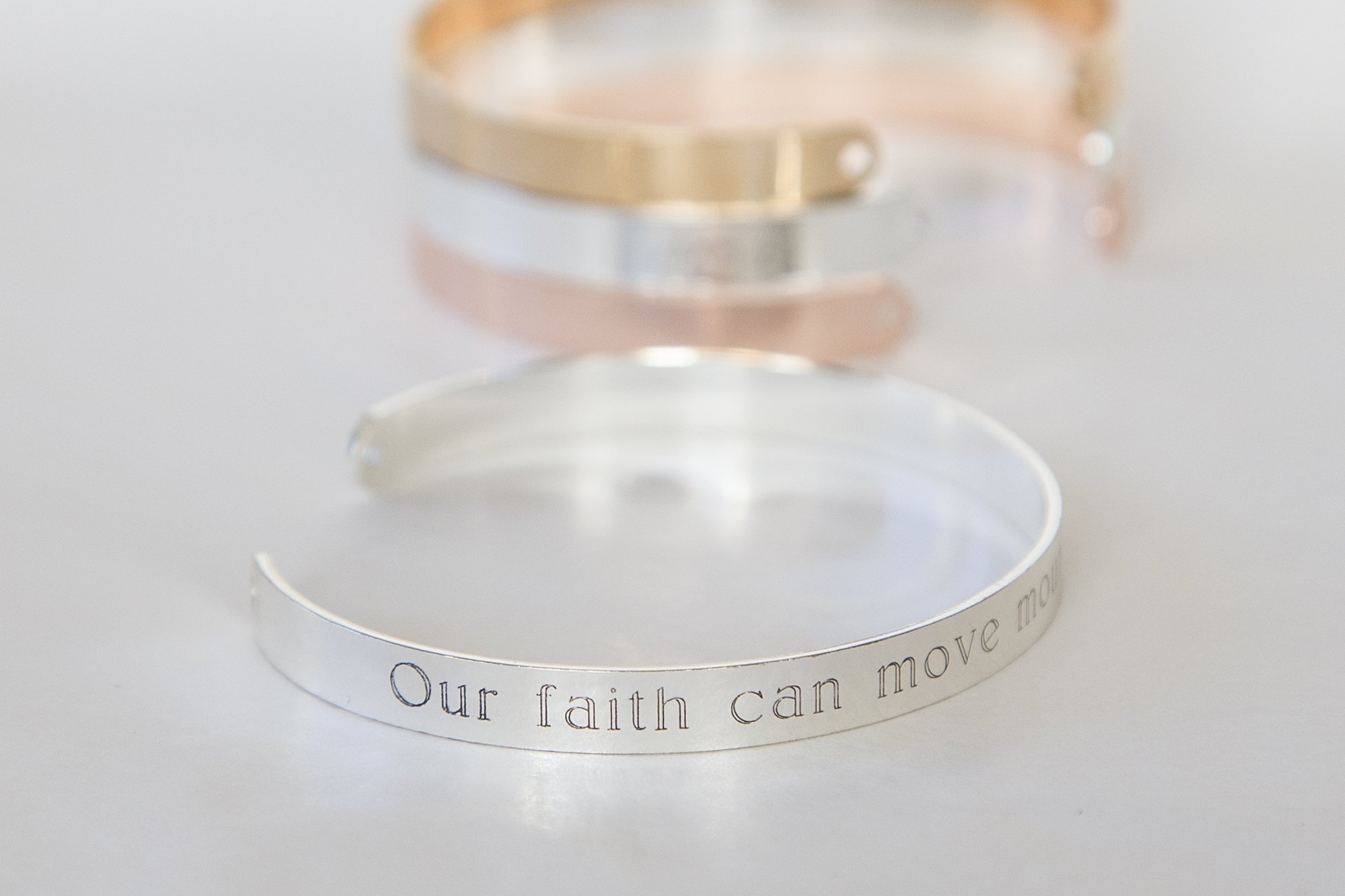 A delicate adjustable bracelet featuring the quote 'Our faith can move mountains' engraved, available in gold, rose gold, and silver finishes.