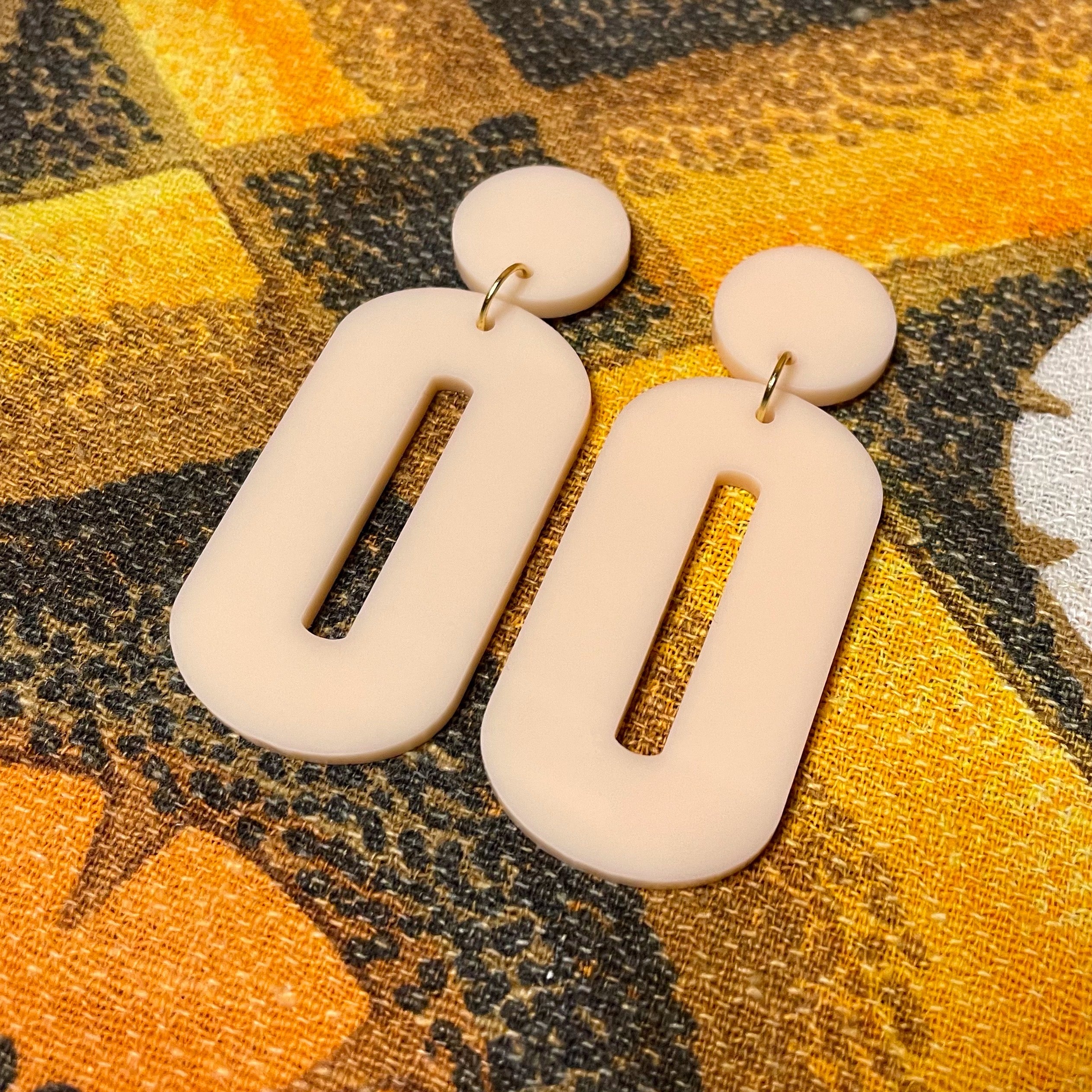 A pair of stylish oval drop earrings made from laser-cut acrylic, showcasing their elegant design and available colors.