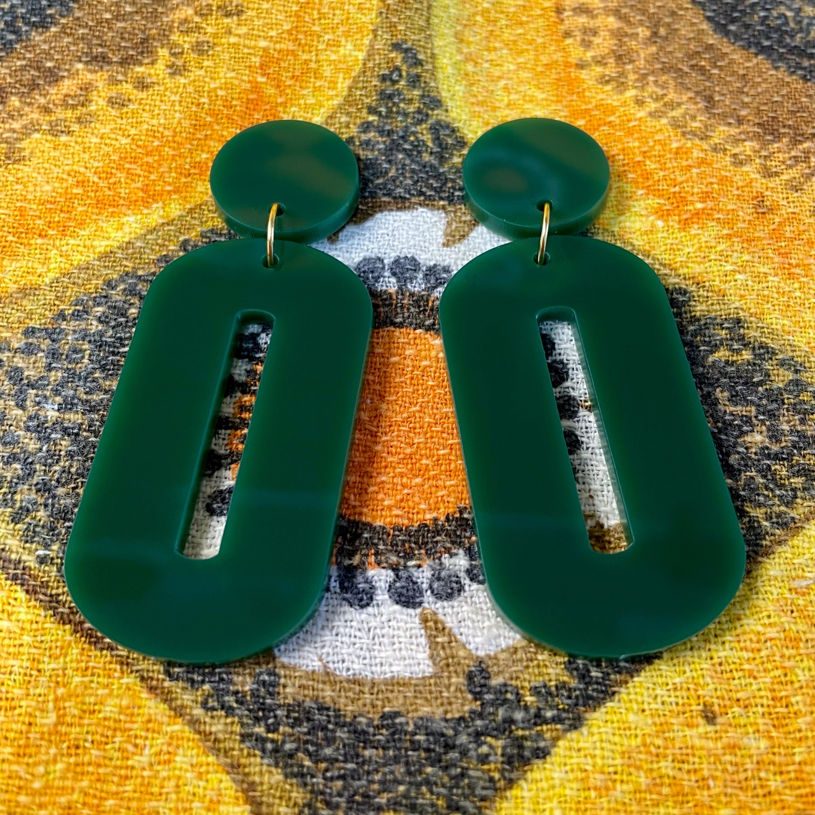 A pair of stylish oval drop earrings made from laser-cut acrylic, showcasing their elegant design and available colors.