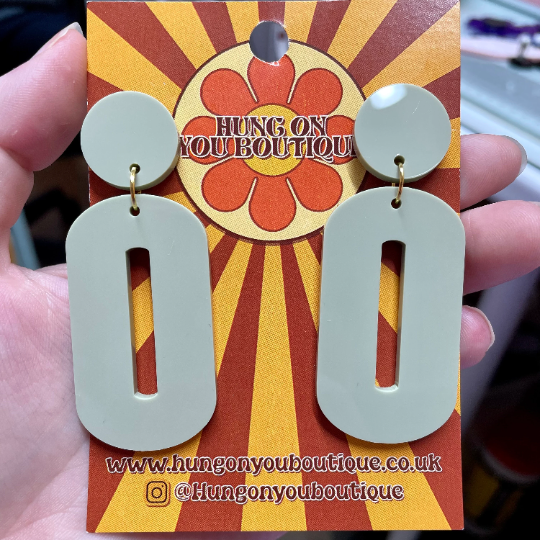 A pair of stylish oval drop earrings made from laser-cut acrylic, showcasing their elegant design and available colors.