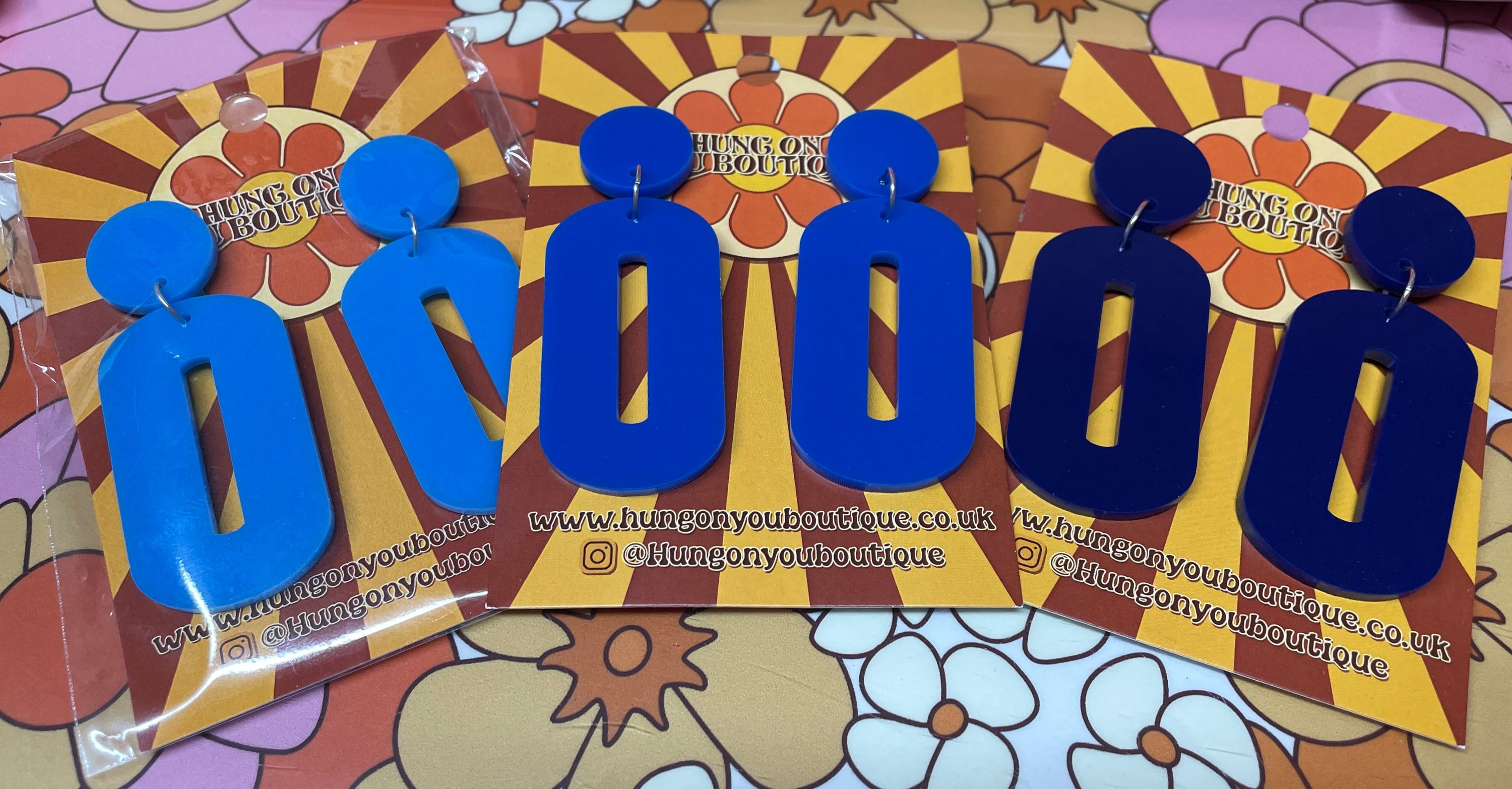 A pair of stylish oval drop earrings made from laser-cut acrylic, showcasing their elegant design and available colors.