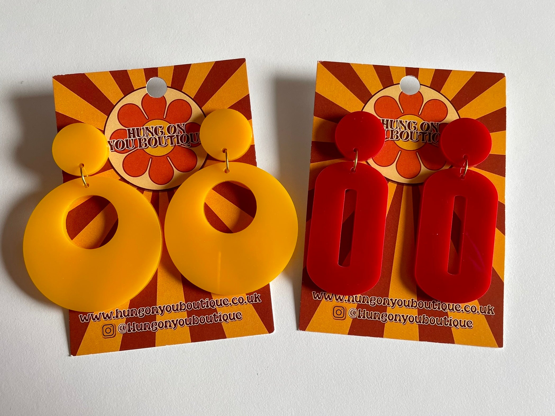 A pair of stylish oval drop earrings made from laser-cut acrylic, showcasing their elegant design and available colors.